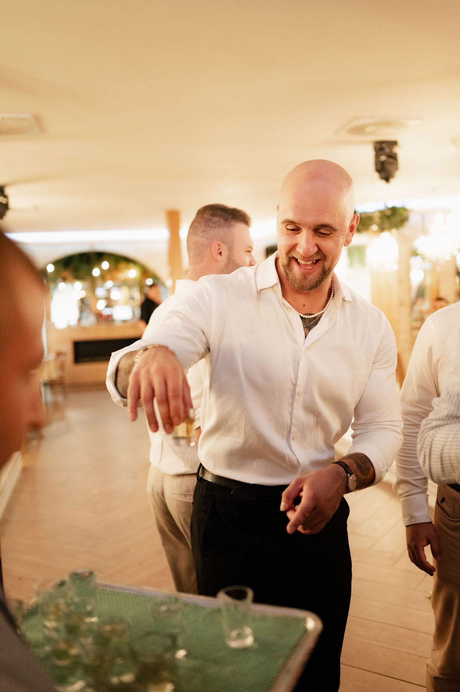 Close-up view of hands preparing food at an elegant event with warm lighting and white chef uniforms.