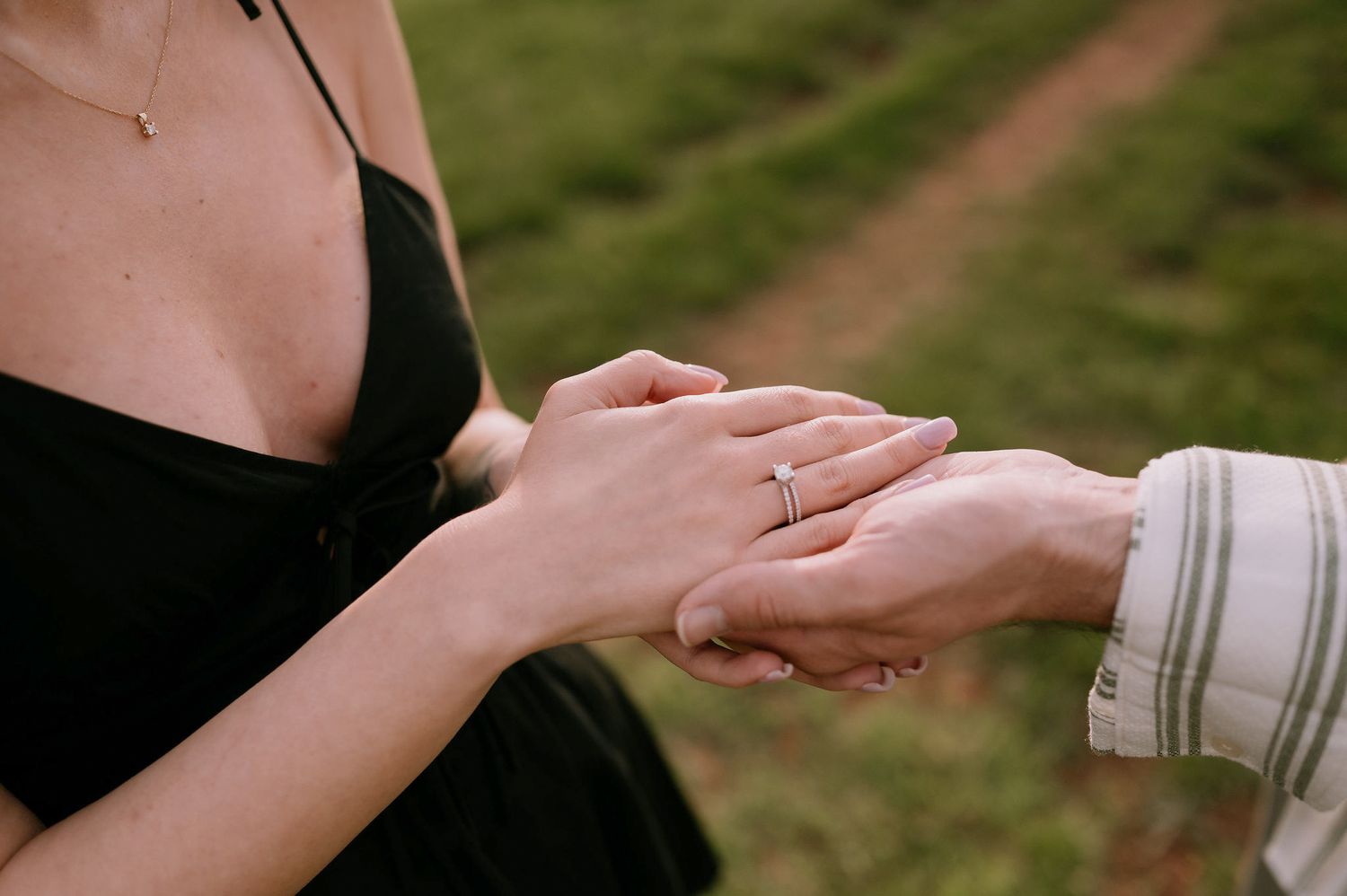 Close-up view of hands exchanging wedding rings during an outdoor ceremony.
