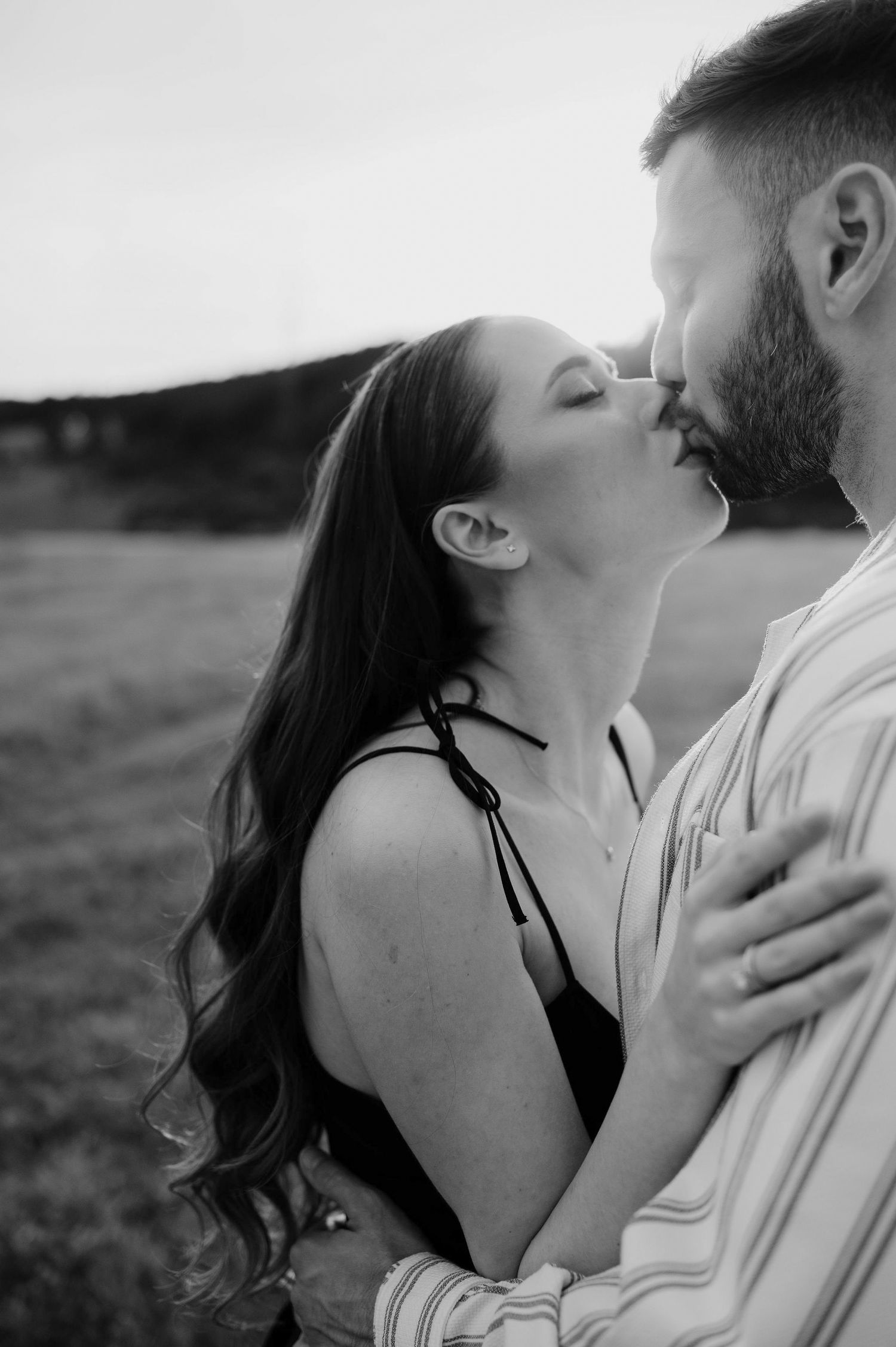 Romantic black and white portrait series of a couple embracing in an intimate outdoor moment.