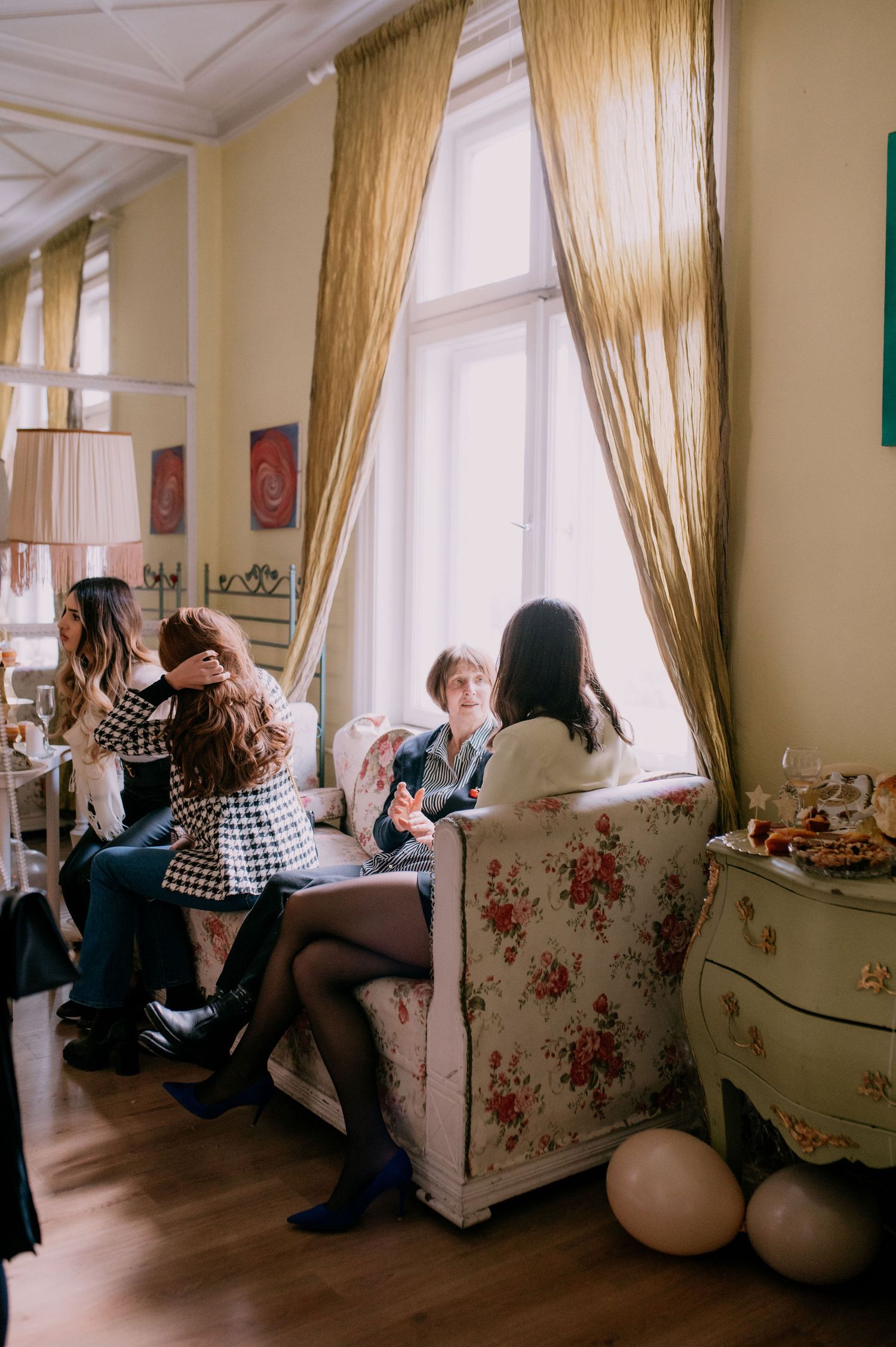 A series of four connected photos showing people relaxing in a cozy living room with floral wallpaper and natural light.