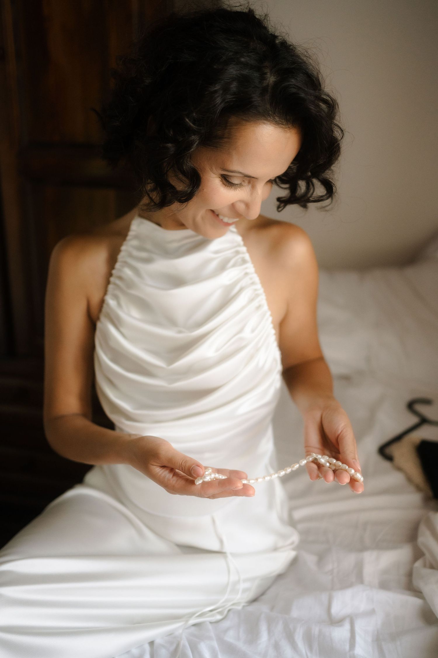 A series of photos showing someone in a white dress sitting on a bed and adjusting their dress details.
