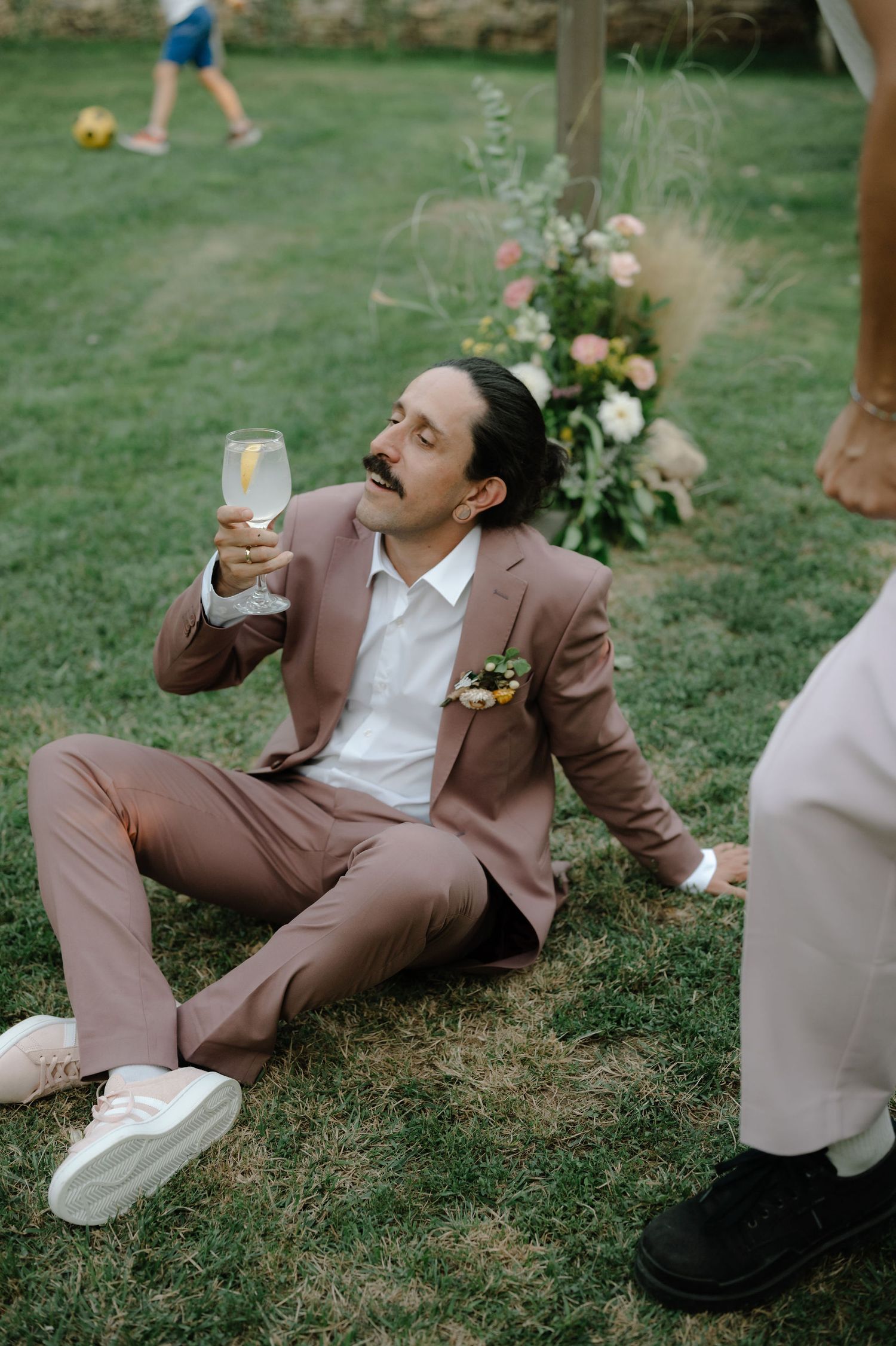 A sequence of photos showing someone in a brown suit and white shirt taking shots at an outdoor event on grass.