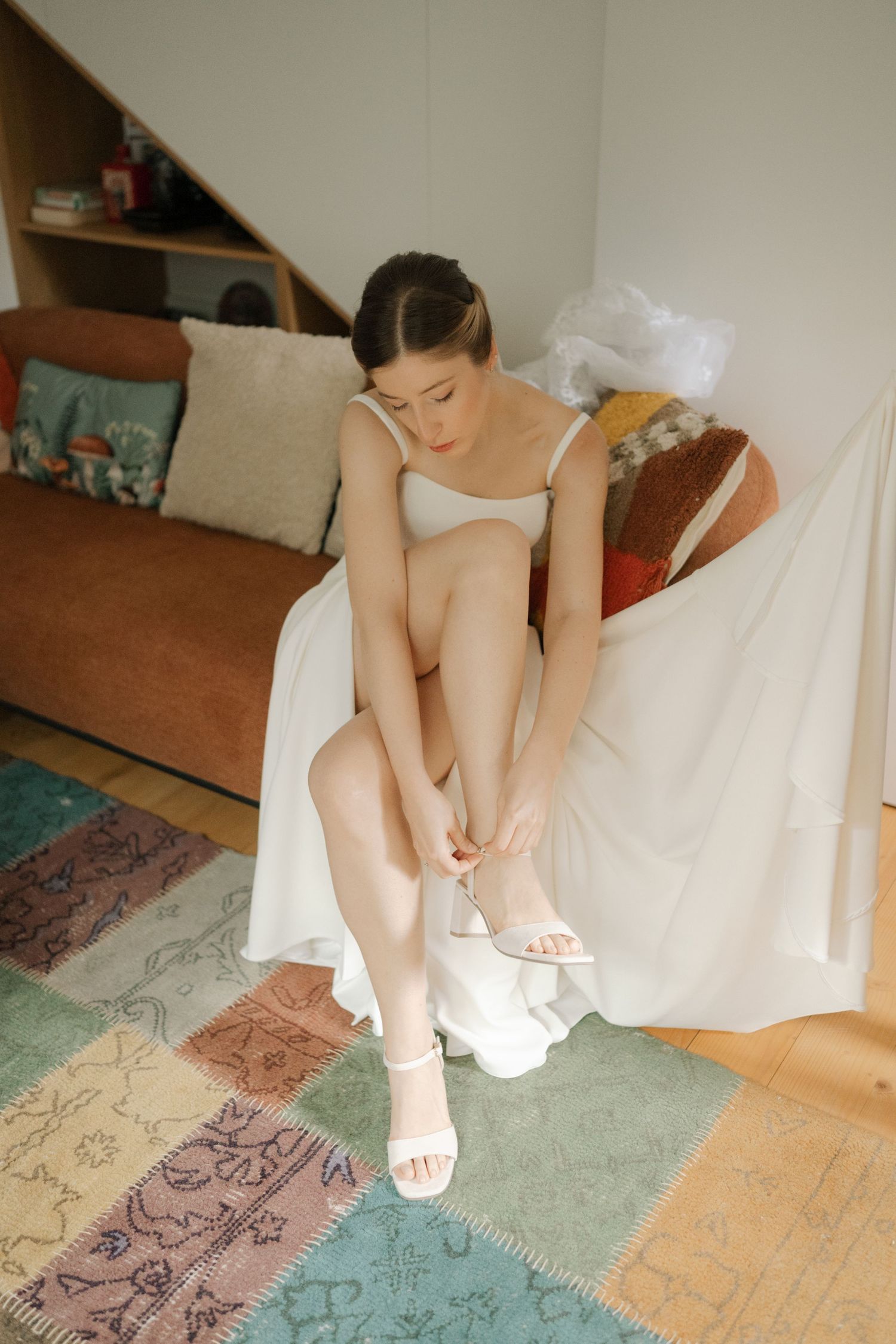 A sequence showing white ballet slippers being put on while sitting on a patterned rug.