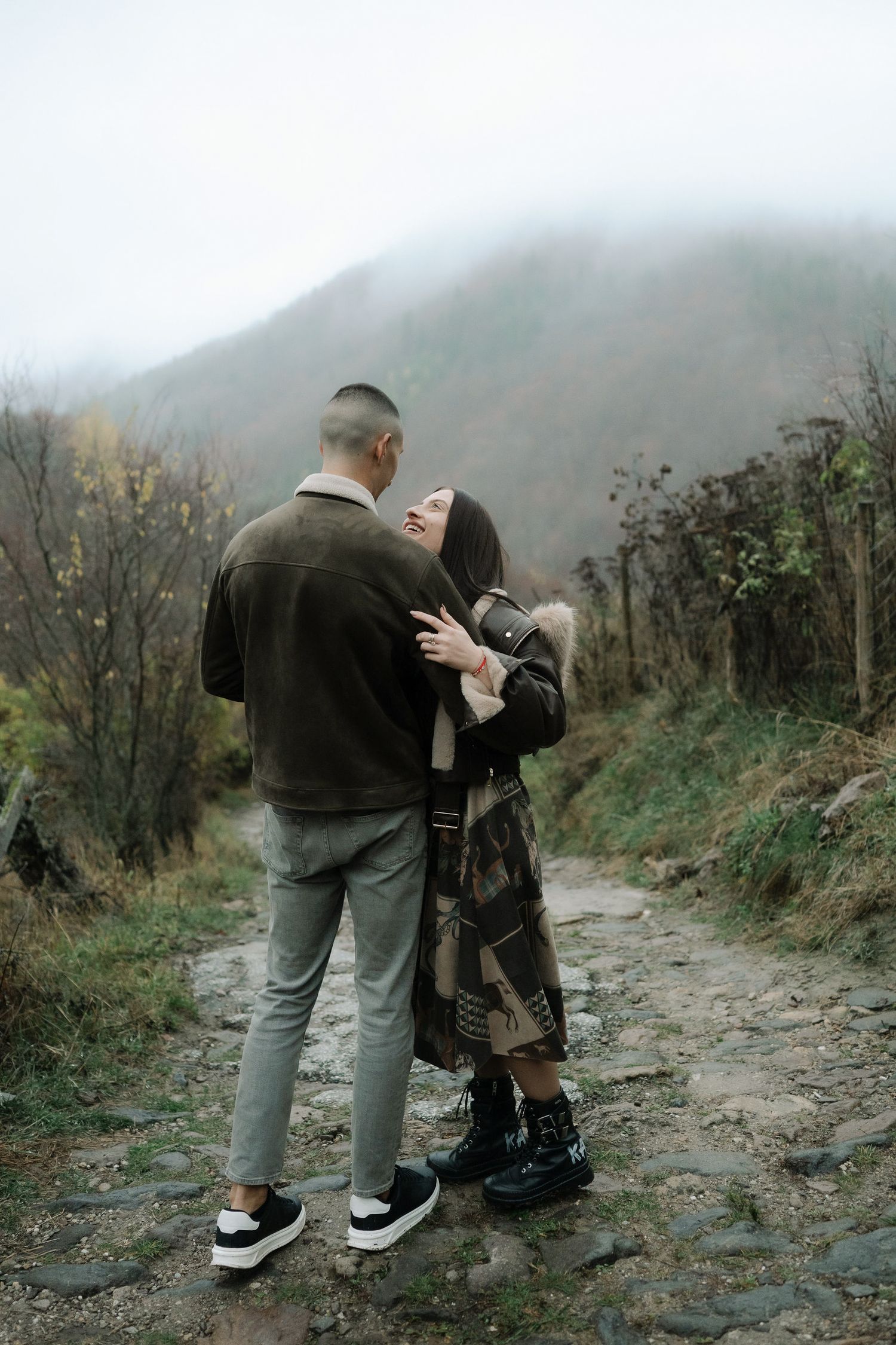 A couple shares an intimate moment on a misty mountain trail, captured in a series of four romantic photographs.