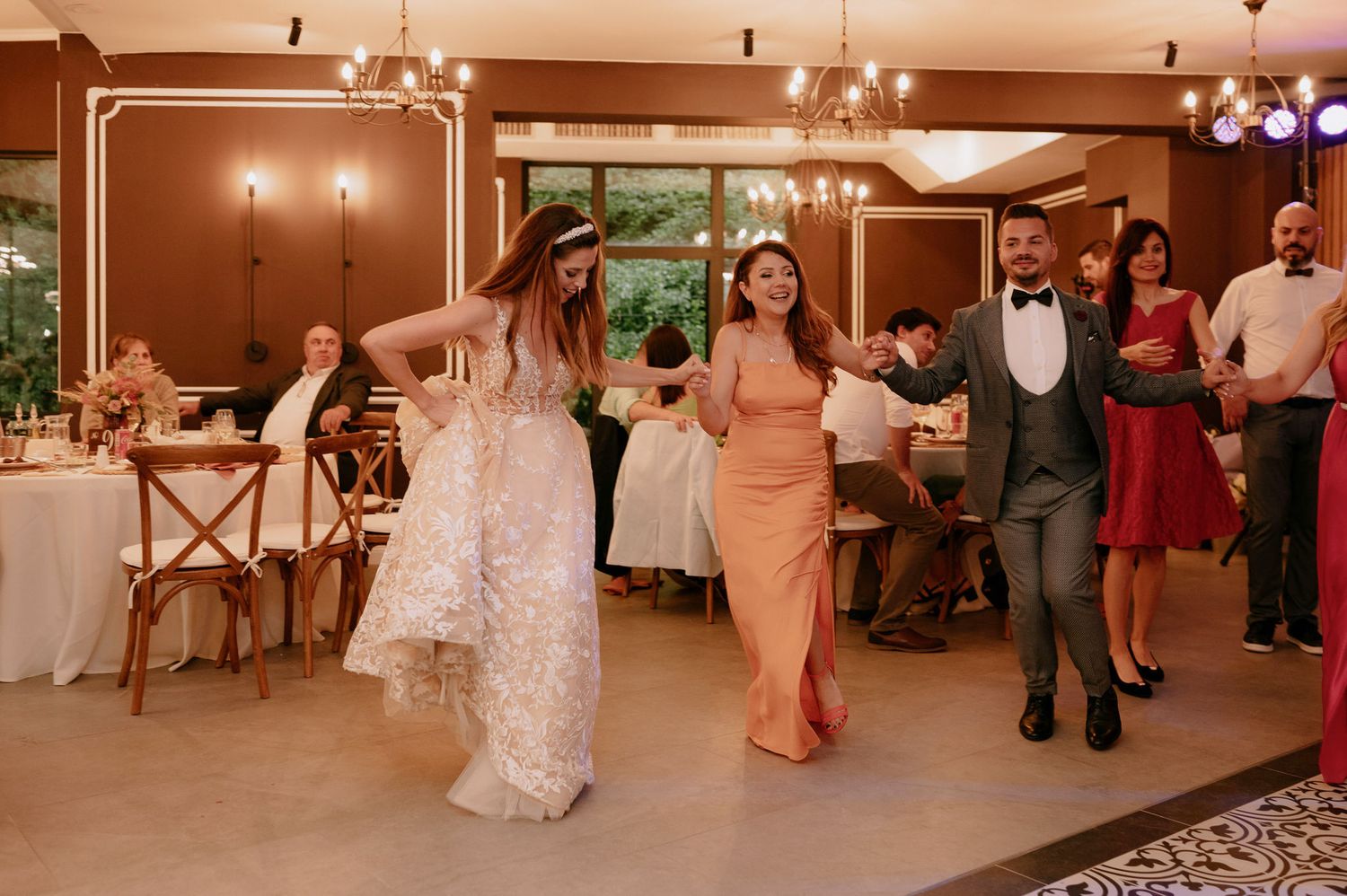 Wedding guests dance and celebrate on a warmly lit wooden dance floor during an evening reception.
