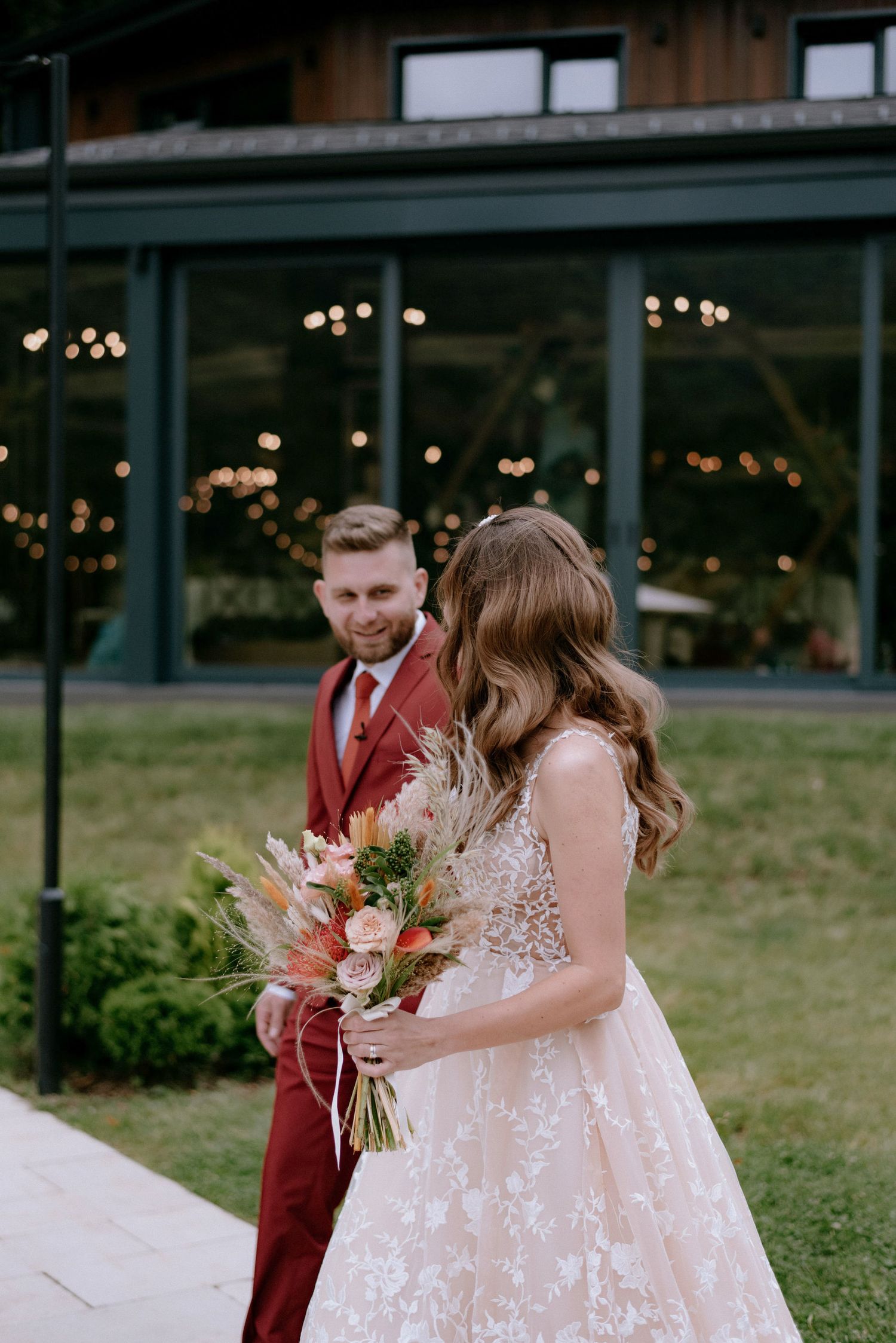 A couple shares a tender moment during their wedding ceremony in a garden setting with burgundy and blush details.