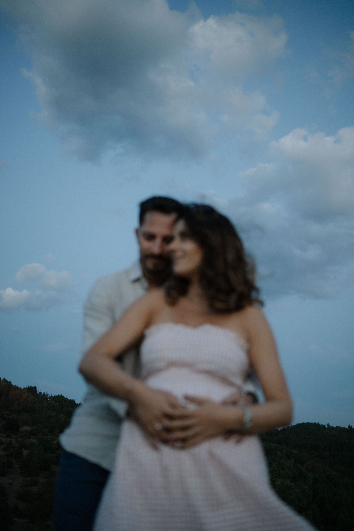 A tender moment captured between a couple during a cloudy outdoor photoshoot.