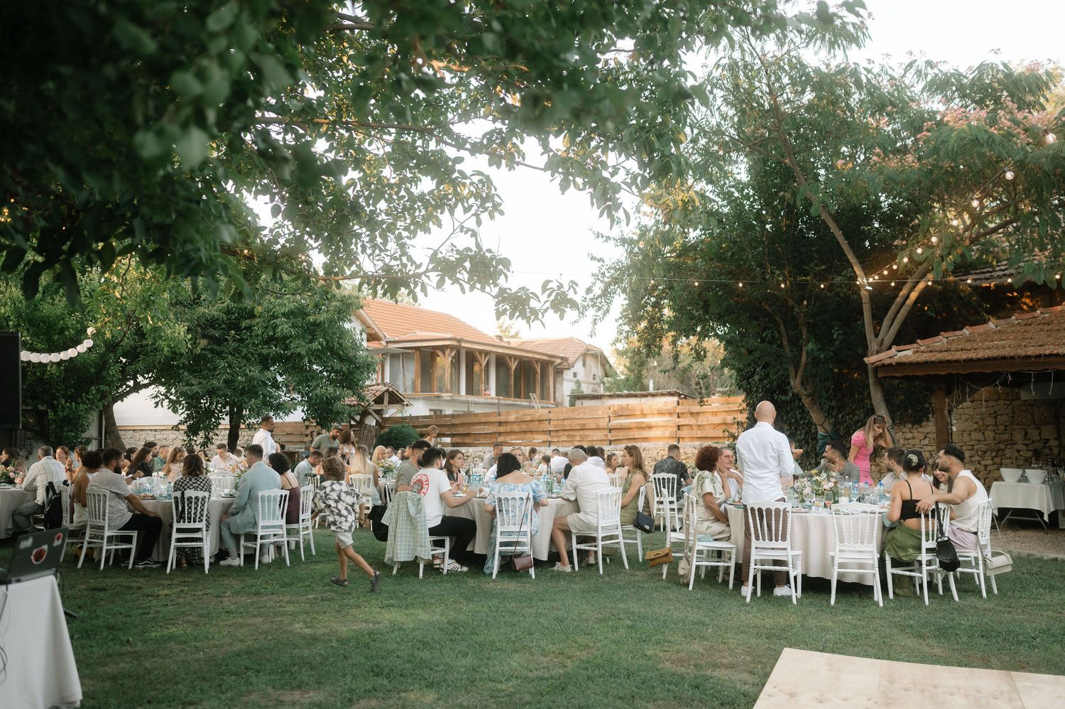 White chairs and tables set up on a grassy lawn for an elegant outdoor garden wedding reception.