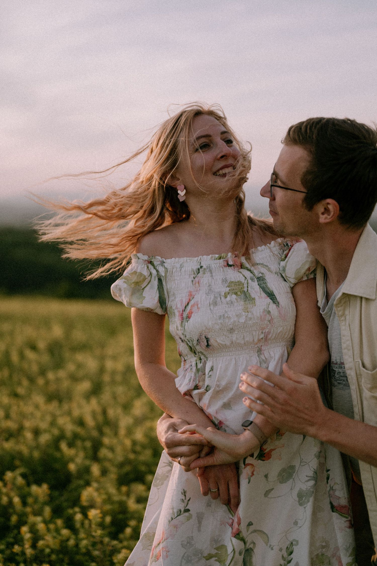 A couple shares an intimate moment while dancing in a blooming meadow at sunset.