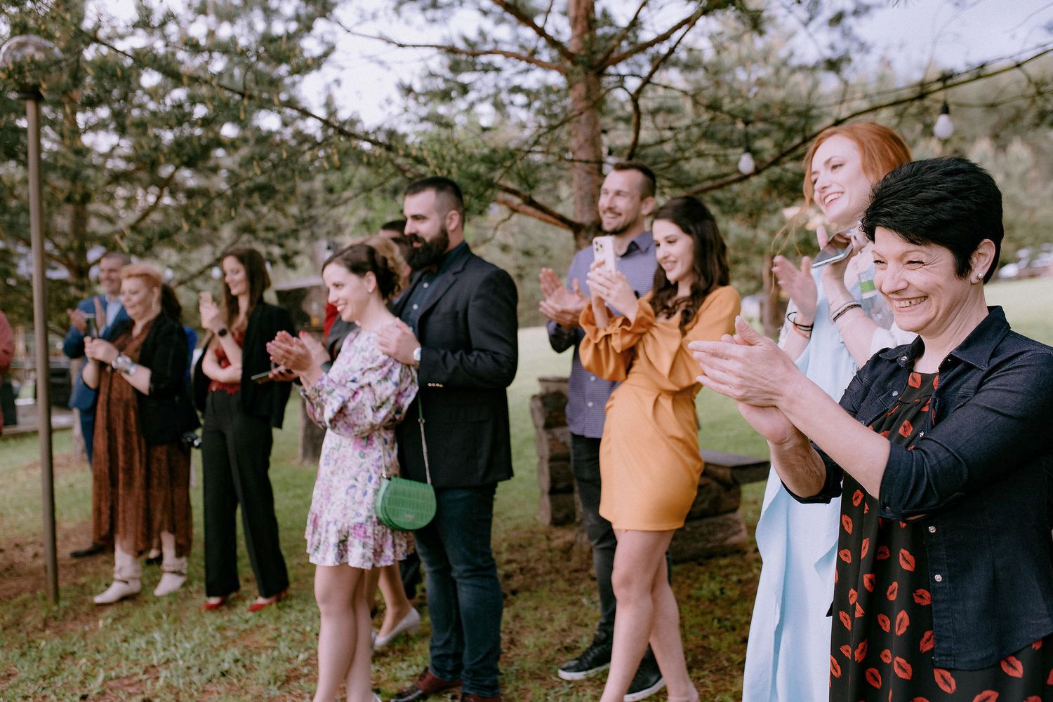 Wedding guests watching emotional ceremony moment in wooded outdoor setting.