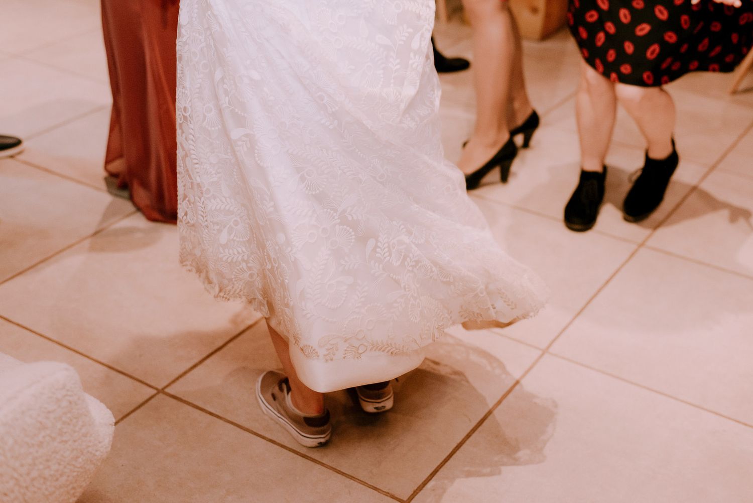 Close-up view of dancing feet and formal attire on a white dance floor.