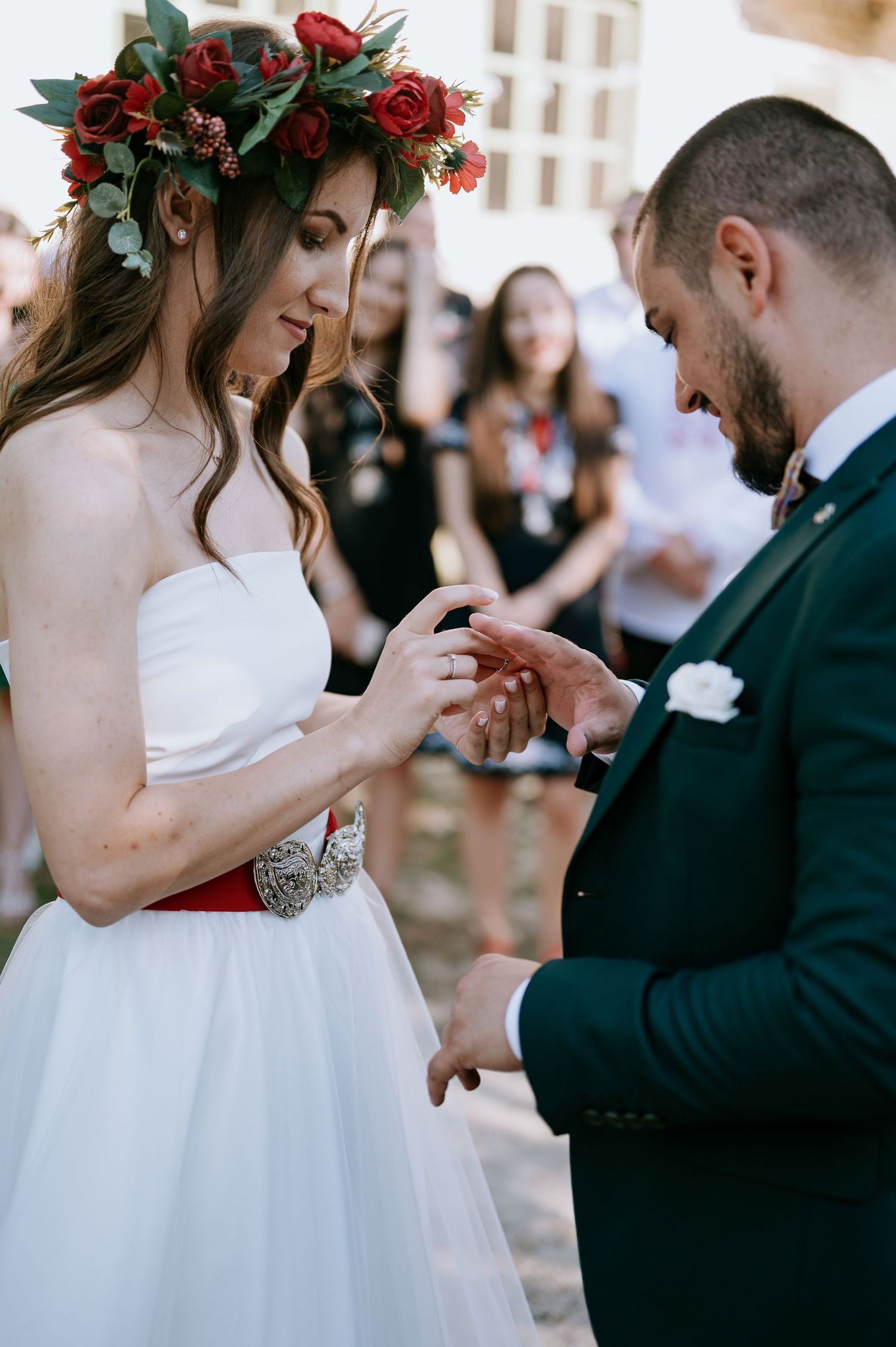 A couple exchanges rings during their outdoor wedding ceremony under white draping.