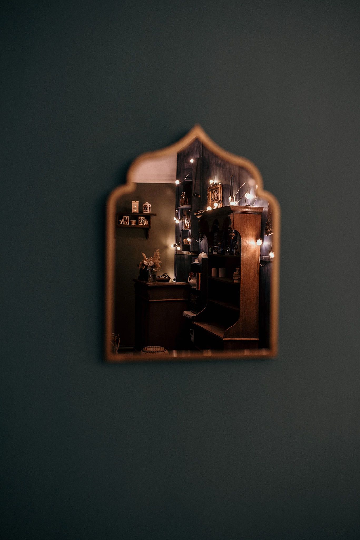 Ornate mirror on dark wall reflecting warm lighting and interior decor.