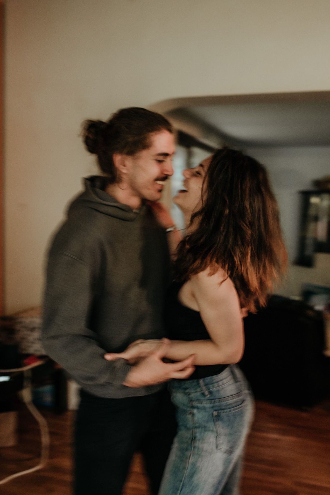 A couple dancing together intimately in a room with wooden floors and soft lighting.