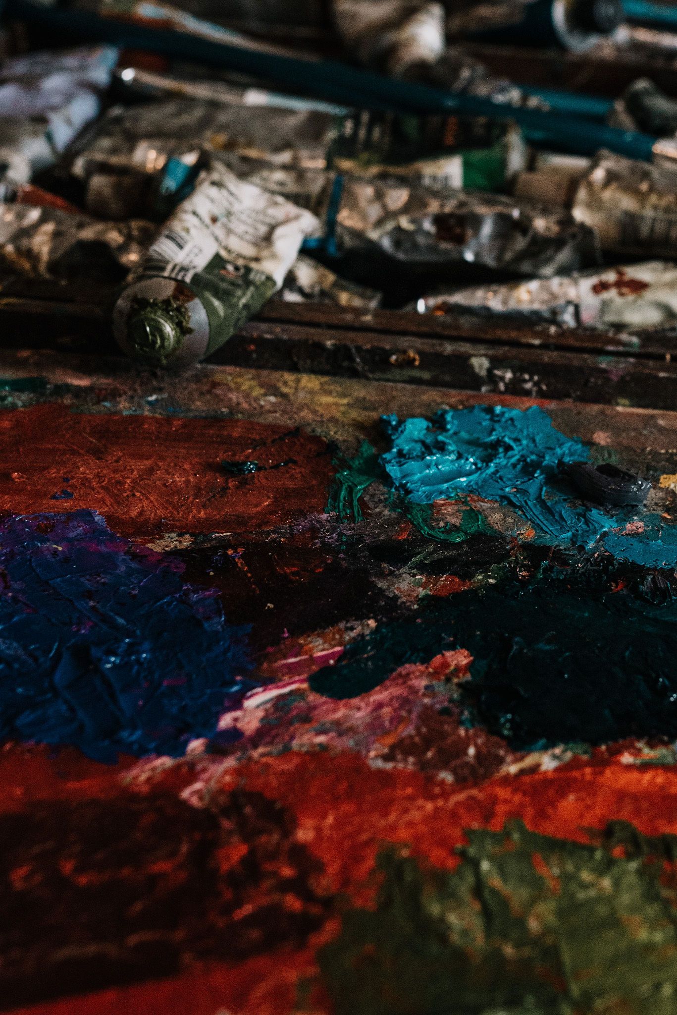 Artist's palette with vibrant smears of red, blue, and turquoise paint.