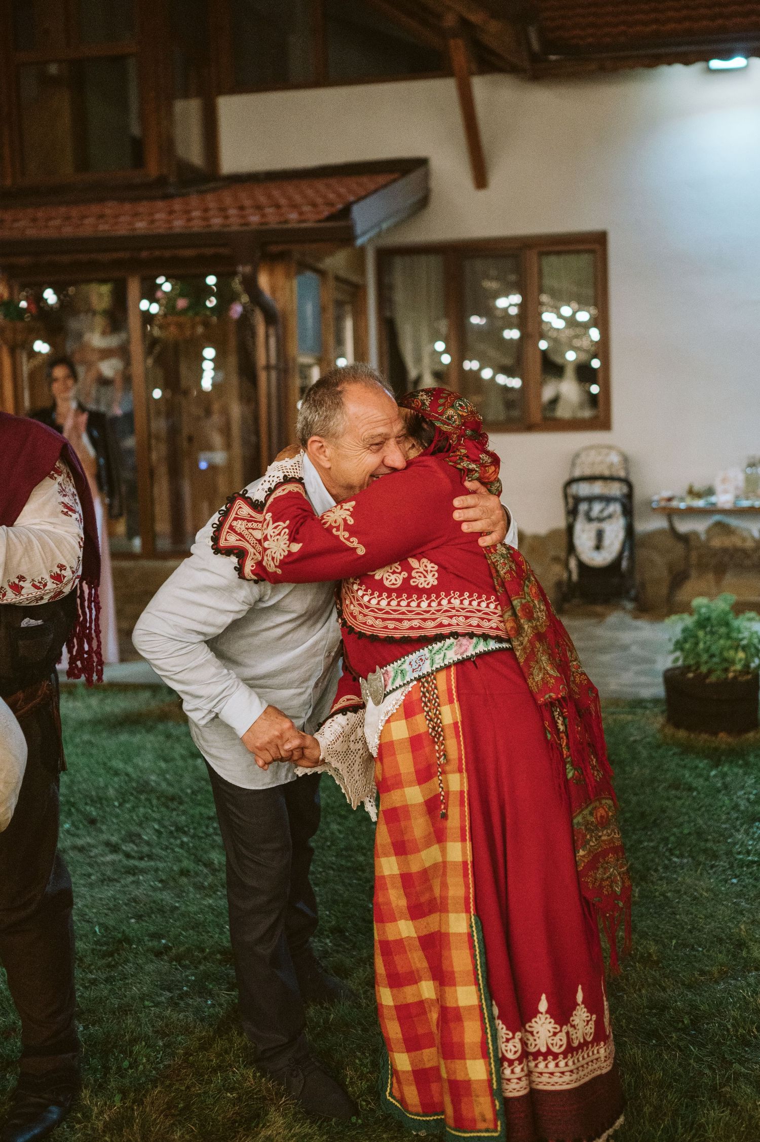 People embracing in traditional folk costumes at outdoor celebration.