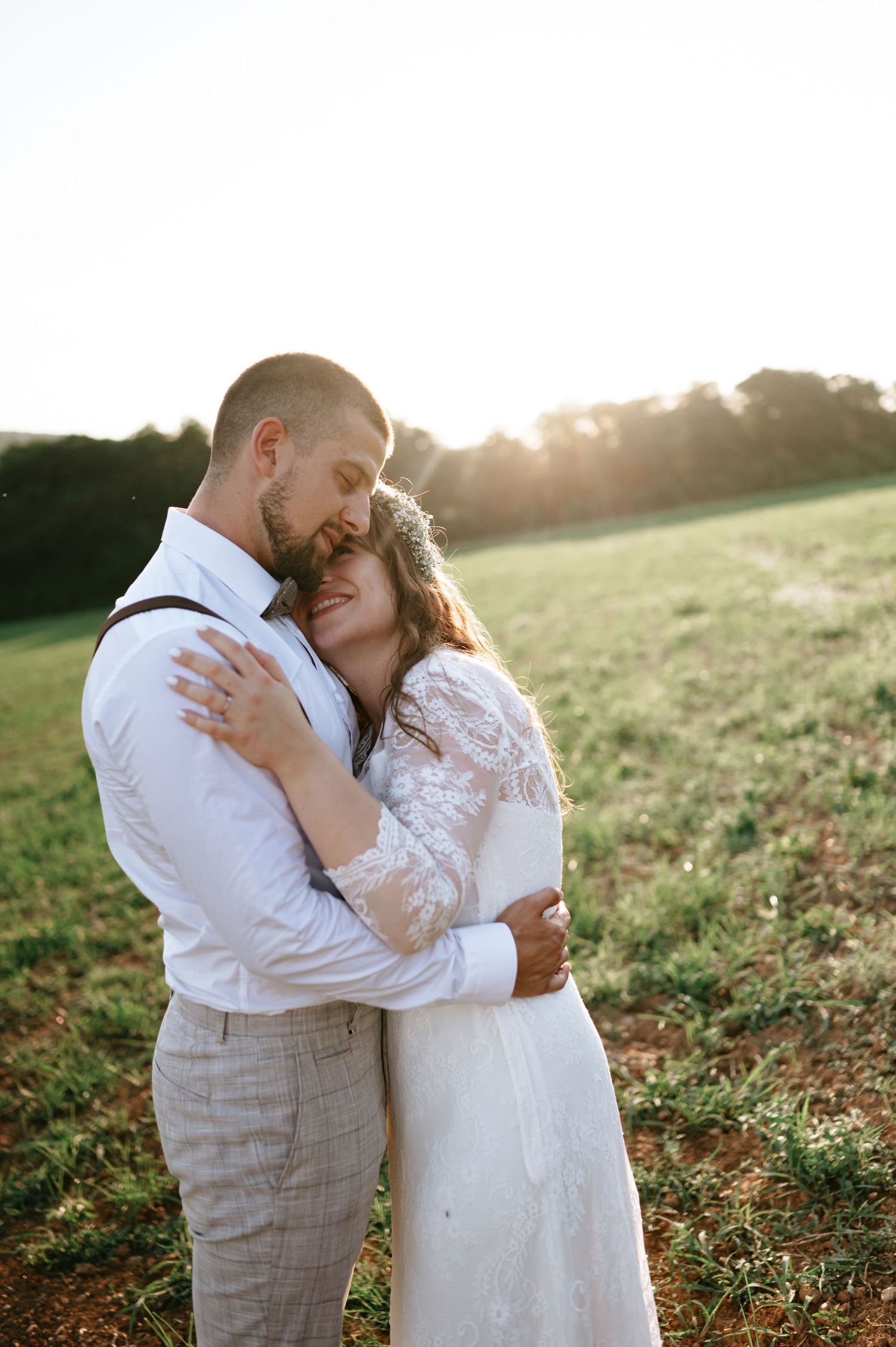 An emotional wedding moment shared between a couple in a sunlit meadow.
