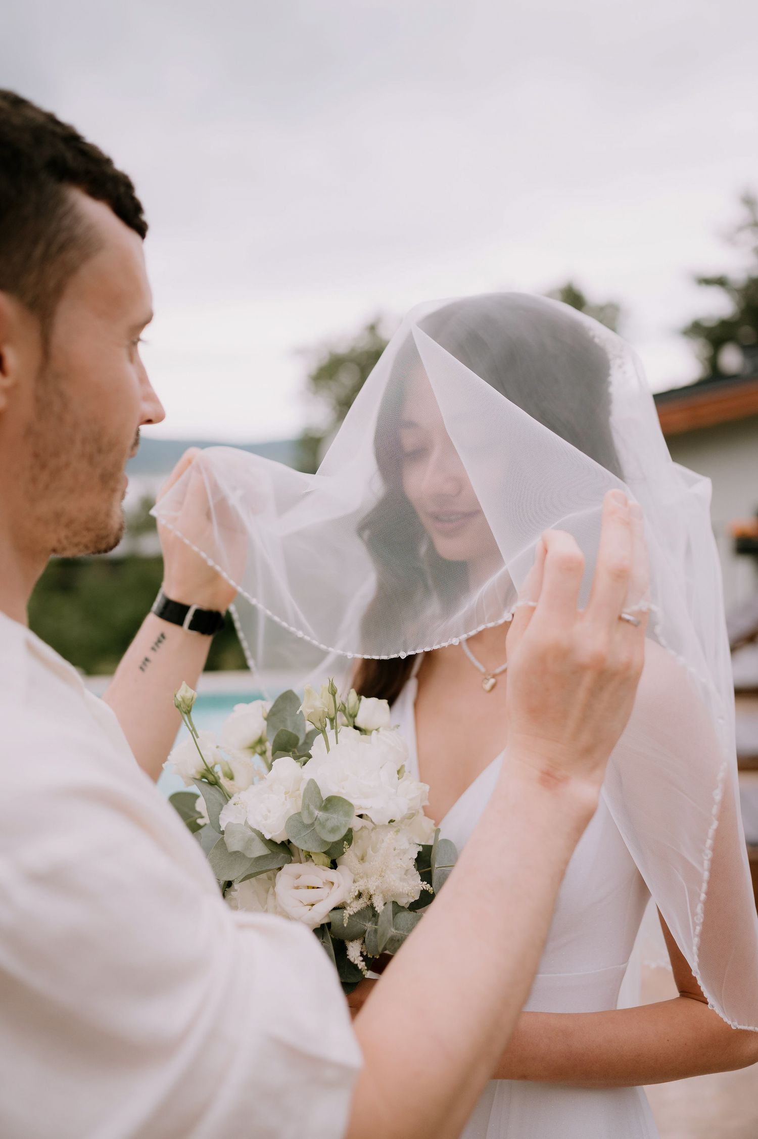 Delicate wedding veil detail shot with white flowers in soft focus.