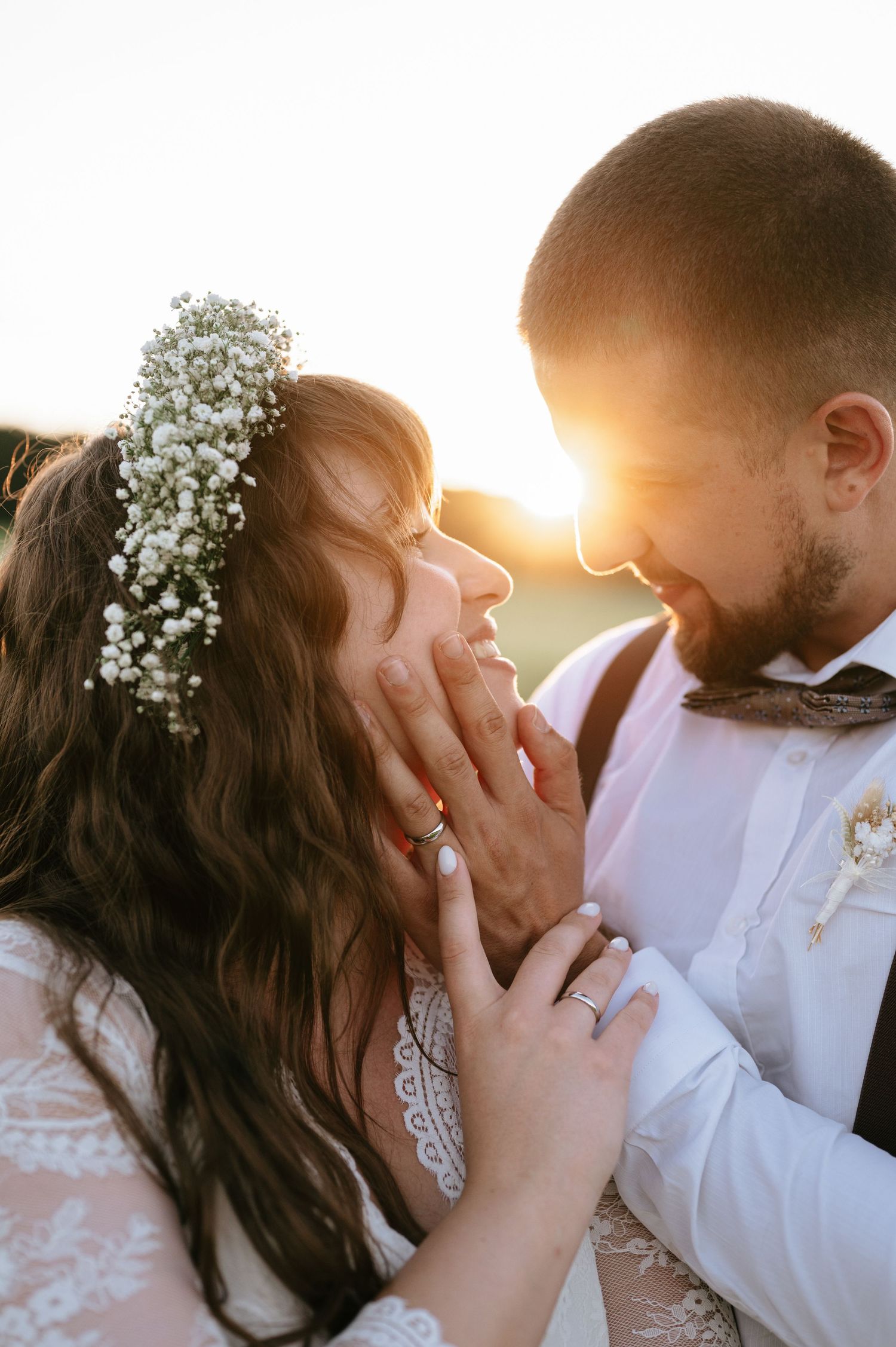 A romantic sunset portrait of newlyweds wearing floral crown and formal attire.