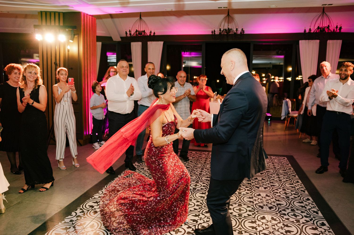 Wedding reception dance floor illuminated with pink lighting and geometric patterns.