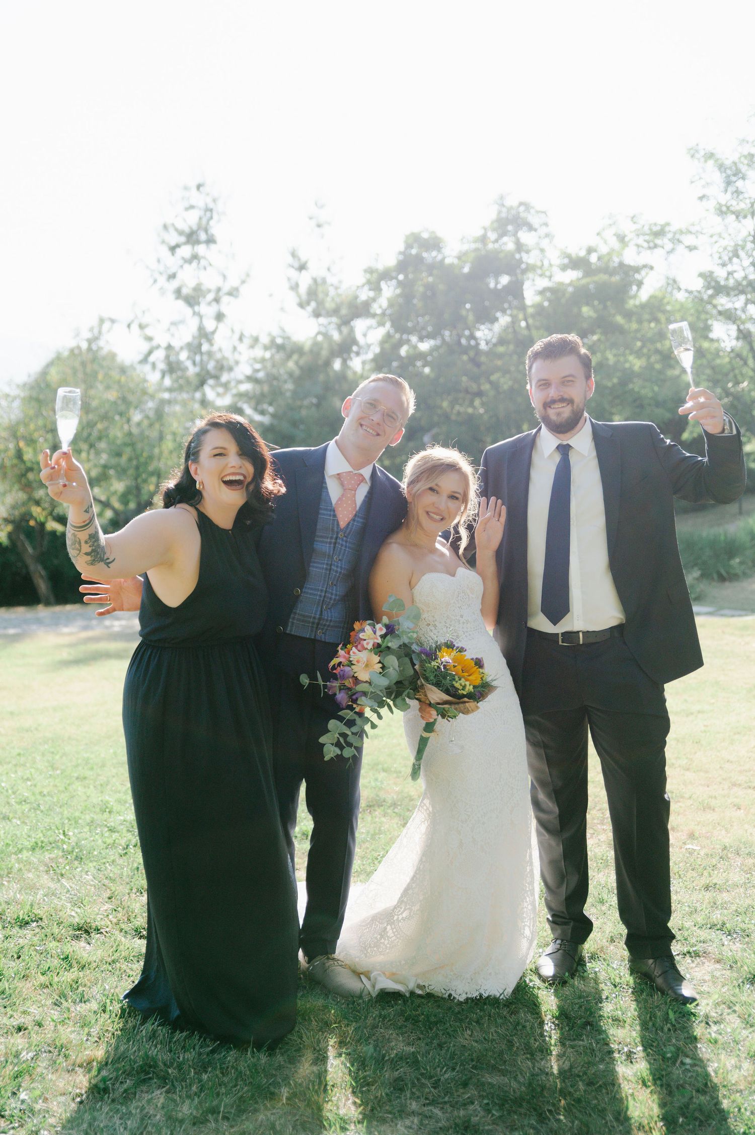 Wedding party laughing and celebrating together outdoors in formal attire.