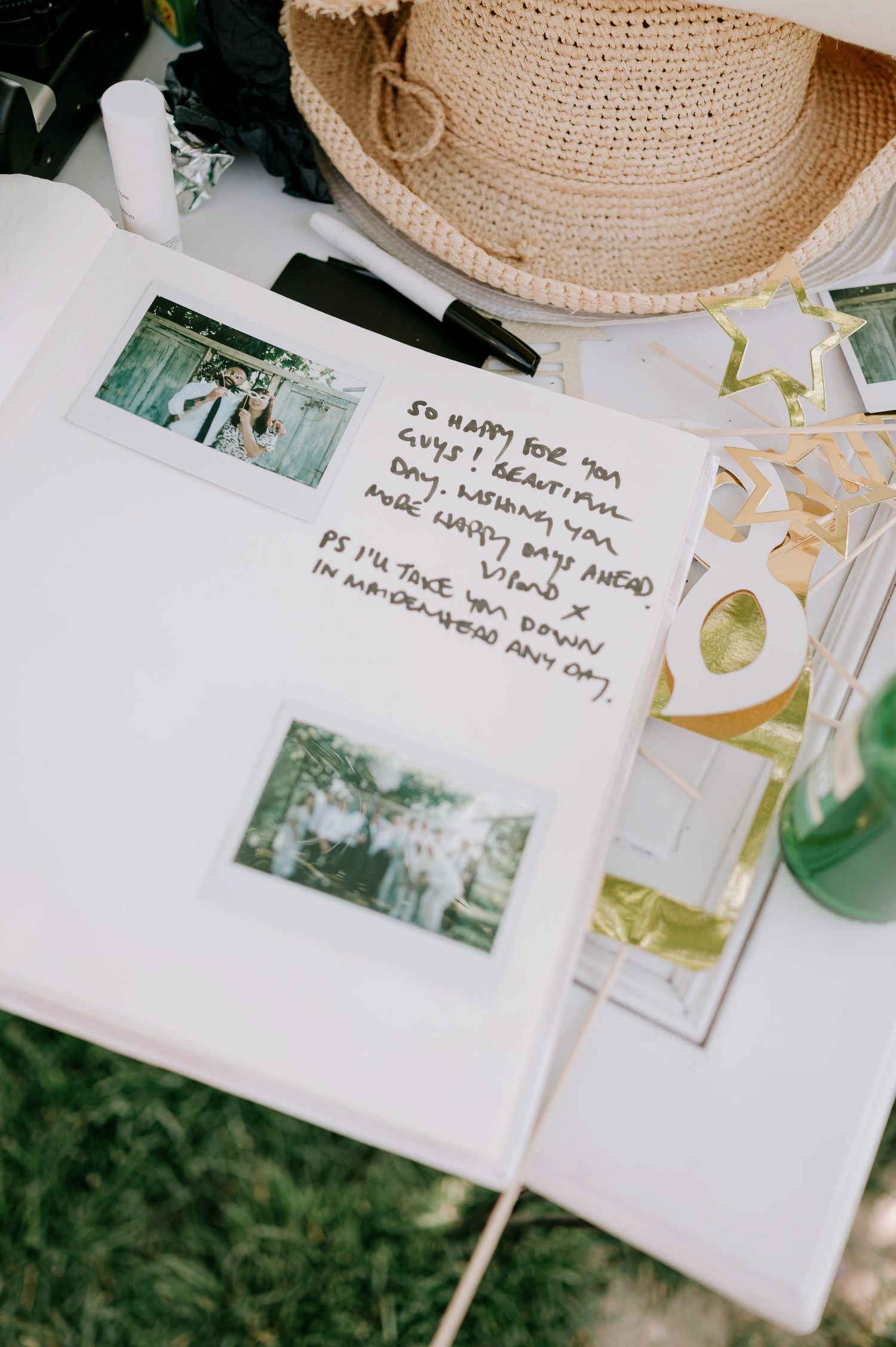 A guestbook display with handwritten notes and photos arranged on a white surface with a straw hat accent.