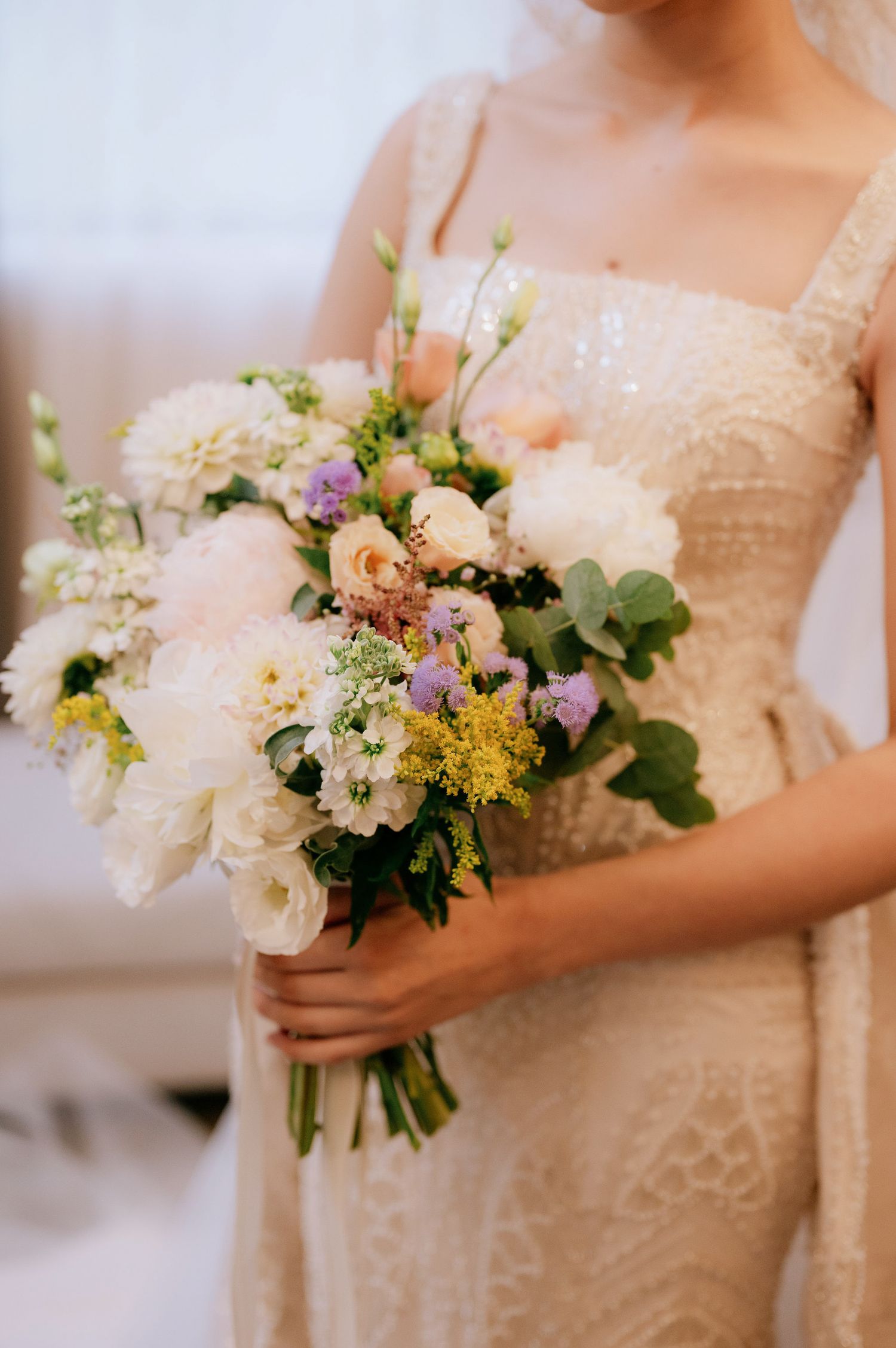 Close-up of romantic bridal bouquet featuring white peonies, roses and mixed pastel flowers.