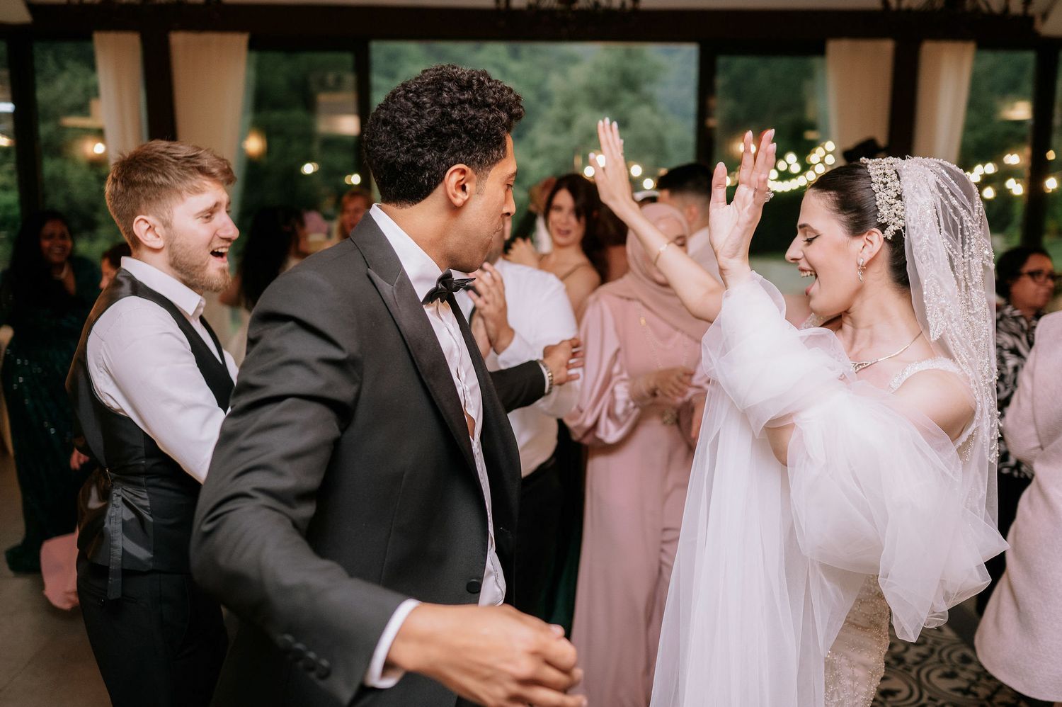 Wedding celebration with guests dancing and clapping in formal attire.
