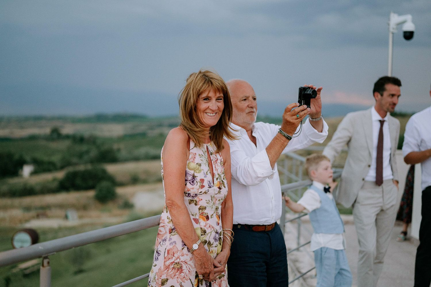 Guests mingle at an outdoor wedding reception with scenic views in the background.