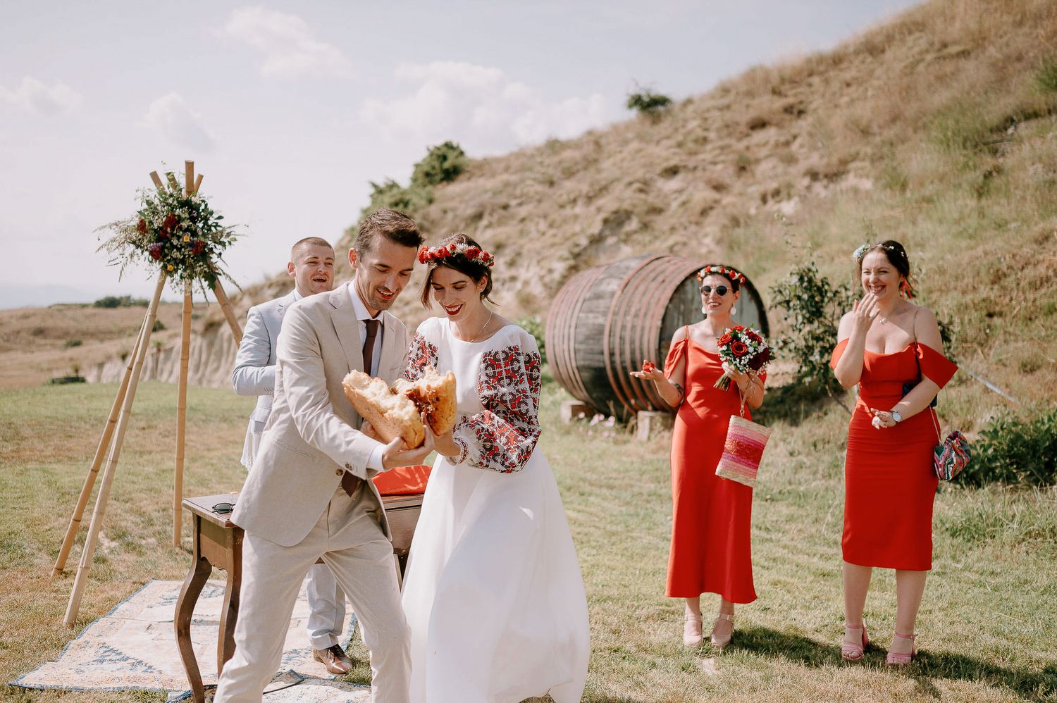 Elegant outdoor wedding scene with bridal party in coral dresses and white decor.