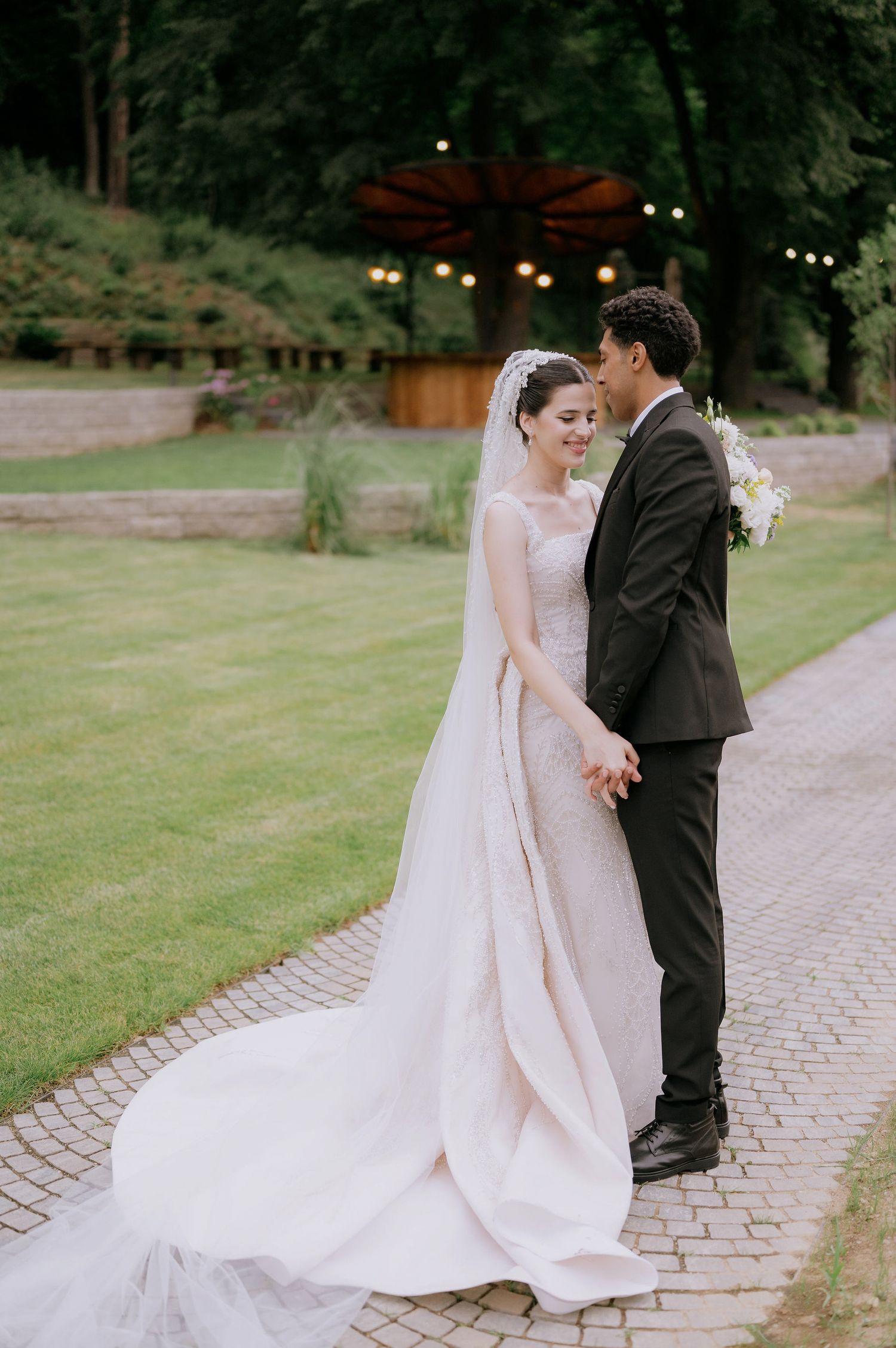 Newlyweds share romantic moments along a winding stone path with a dramatic wedding dress train.