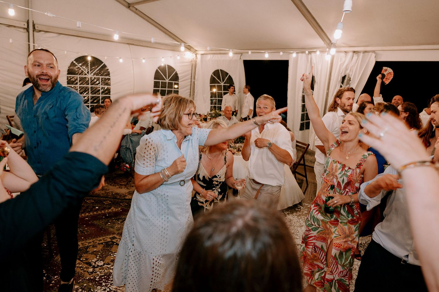 Wedding reception party with guests dancing and celebrating in an elegant tent venue.