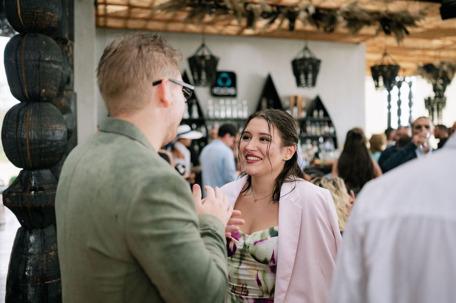 People socializing at an indoor event with white walls and decorative elements.