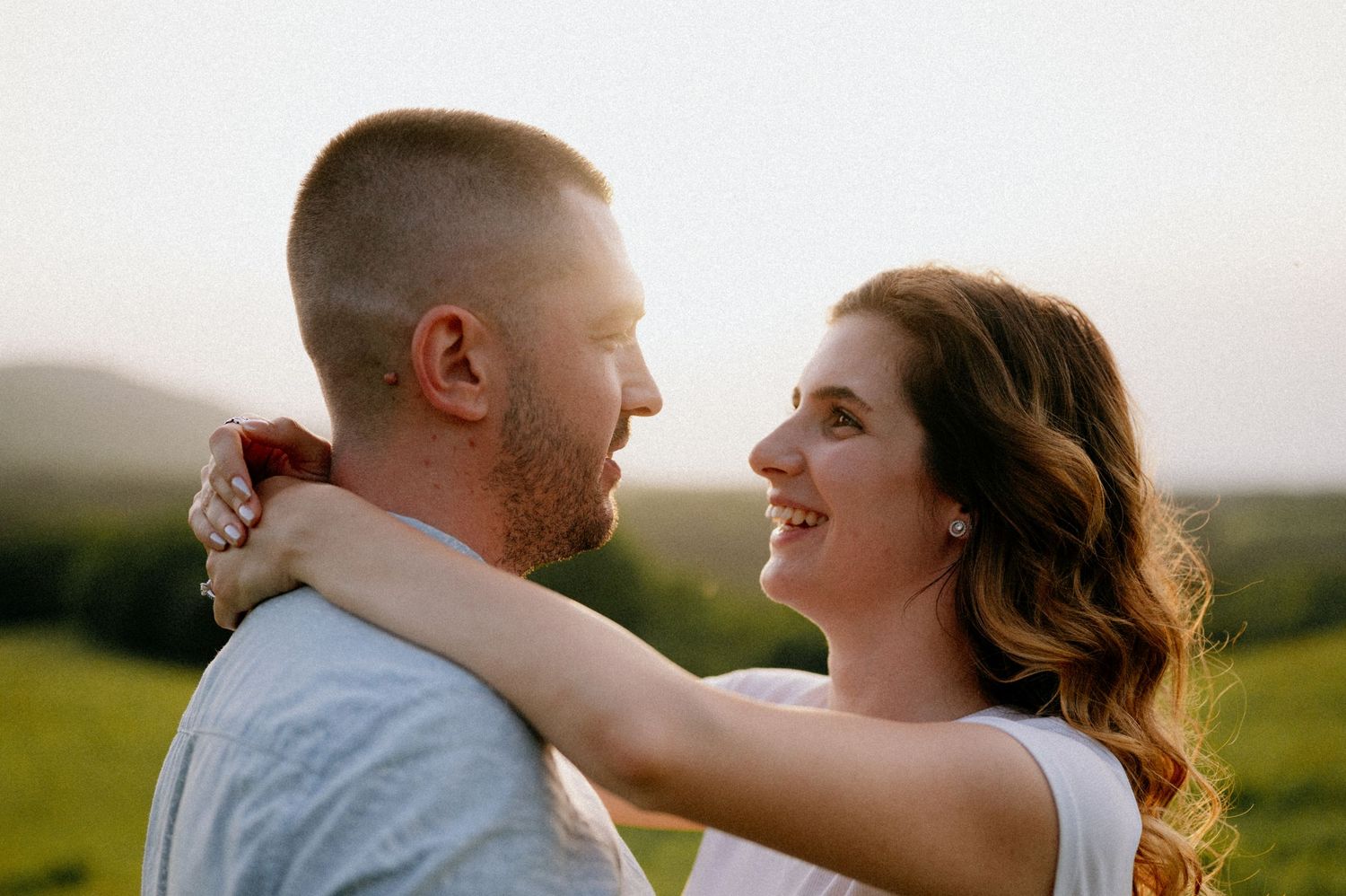 Couple in white shirts embracing during golden hour photography.