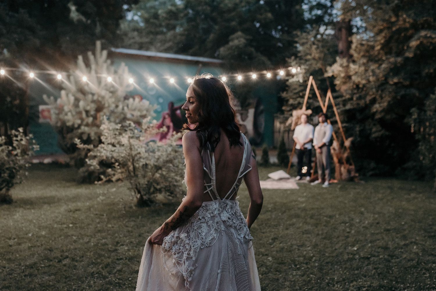 Couple shares an intimate moment during their outdoor wedding ceremony under a flowering tree at sunset.