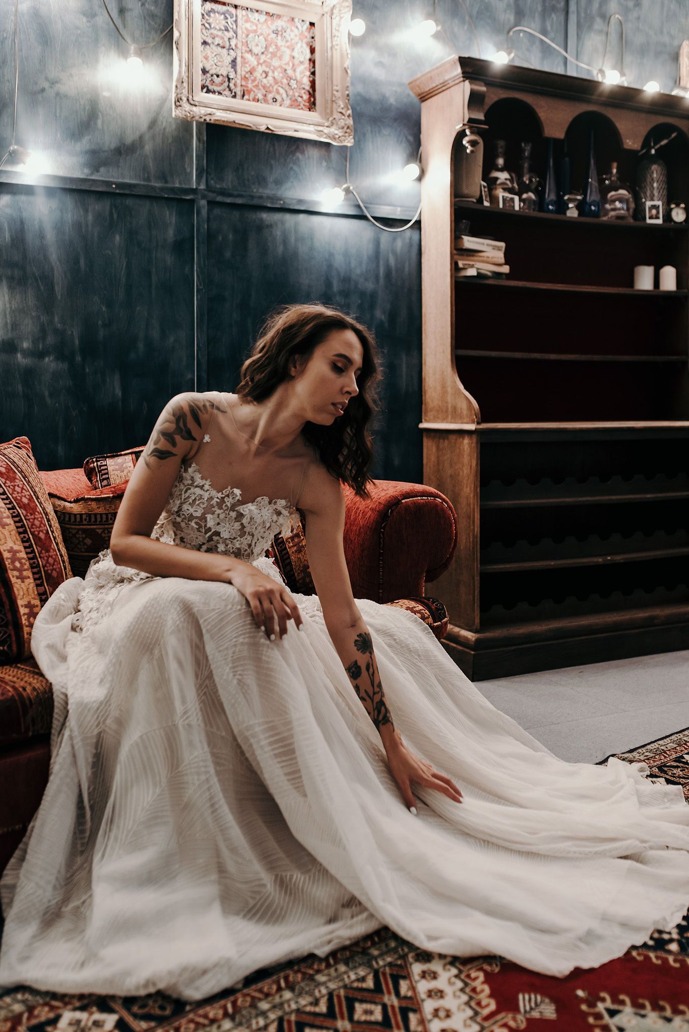 Artistic bridal portrait in moody lighting showing flowing white gown against dark walls.