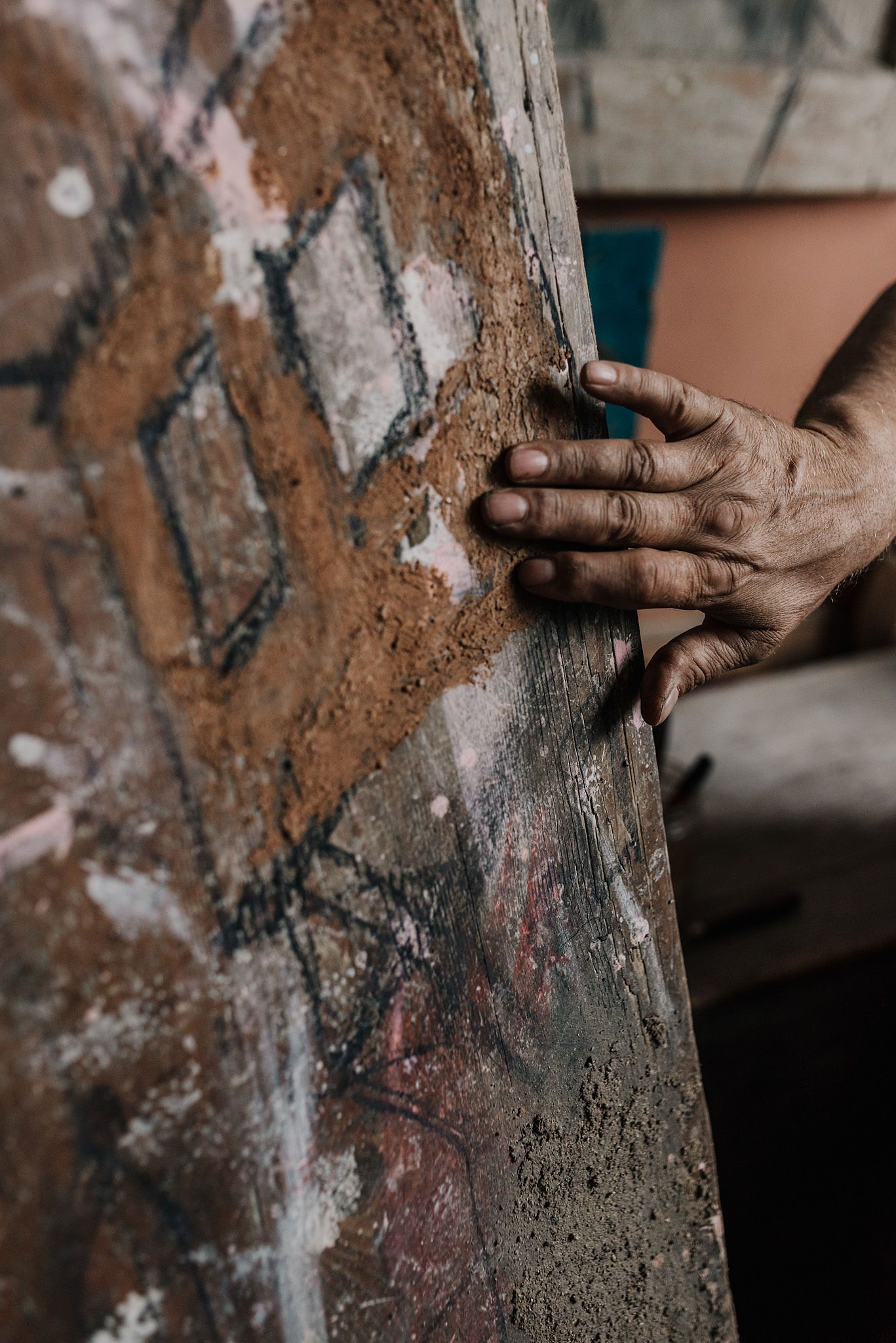Hands touching textured artwork surface showing detail work in progress.