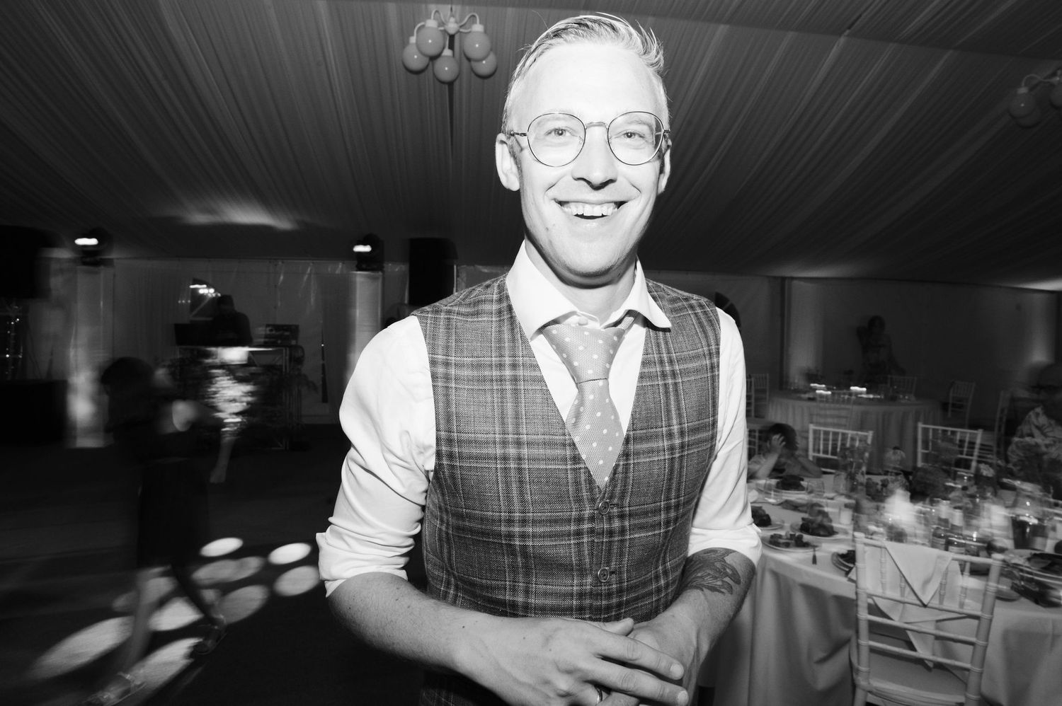 A series of black and white photos showing someone in glasses and a vest at what appears to be a wedding reception.
