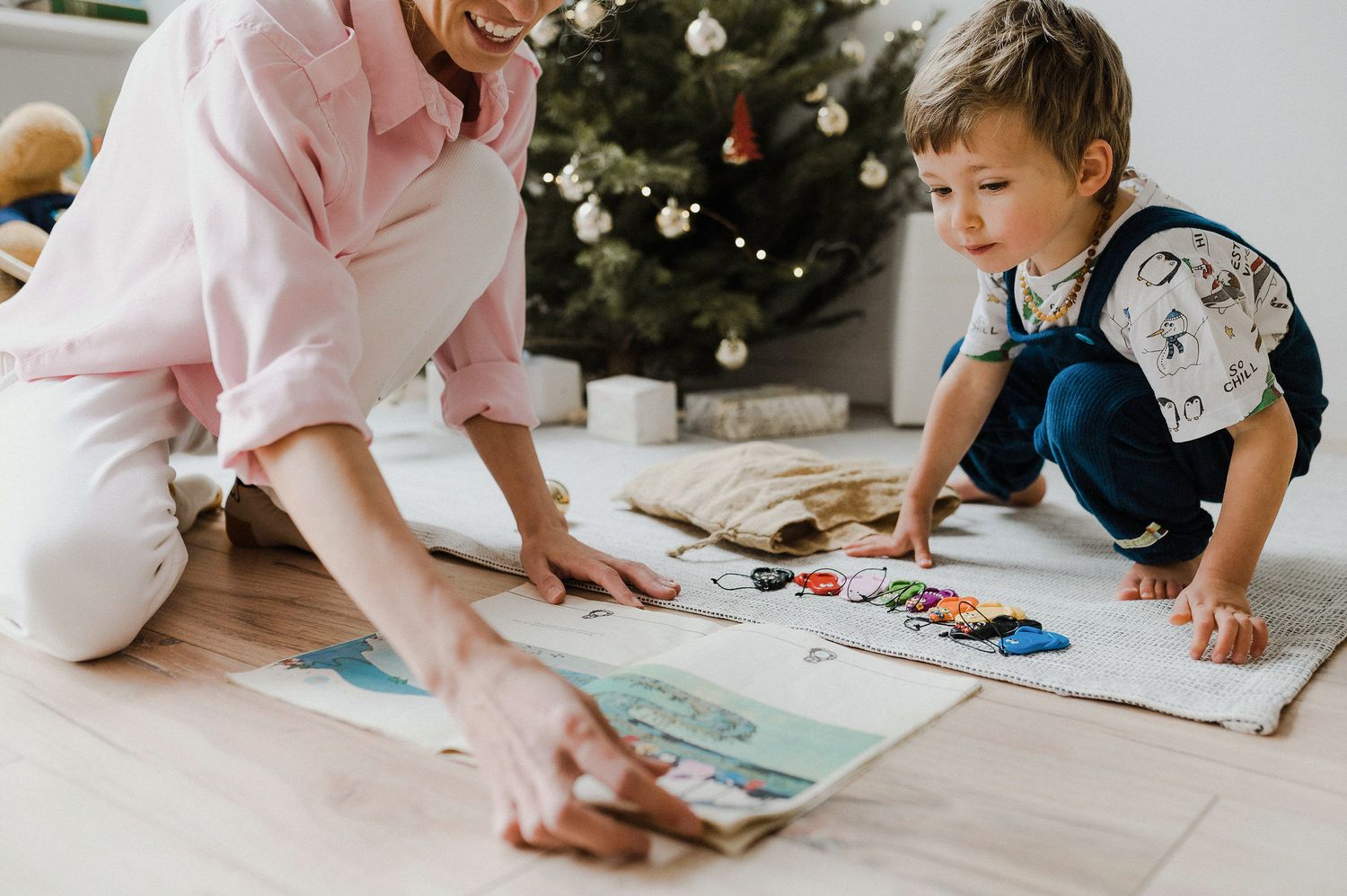 Parent and child lying on floor doing arts and crafts together with colored markers and paper.