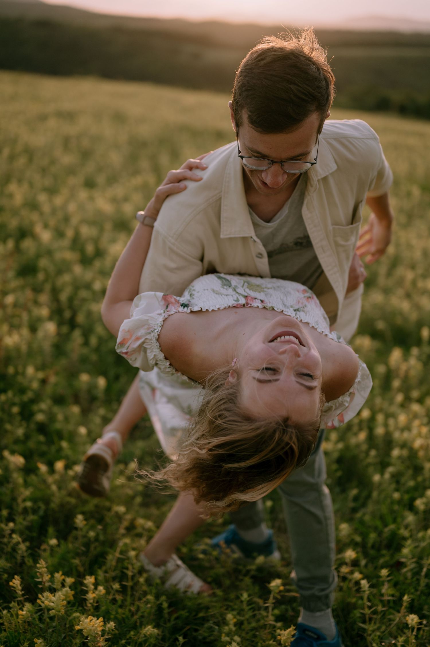 Couple dancing and dipping in a wildflower meadow at sunset.