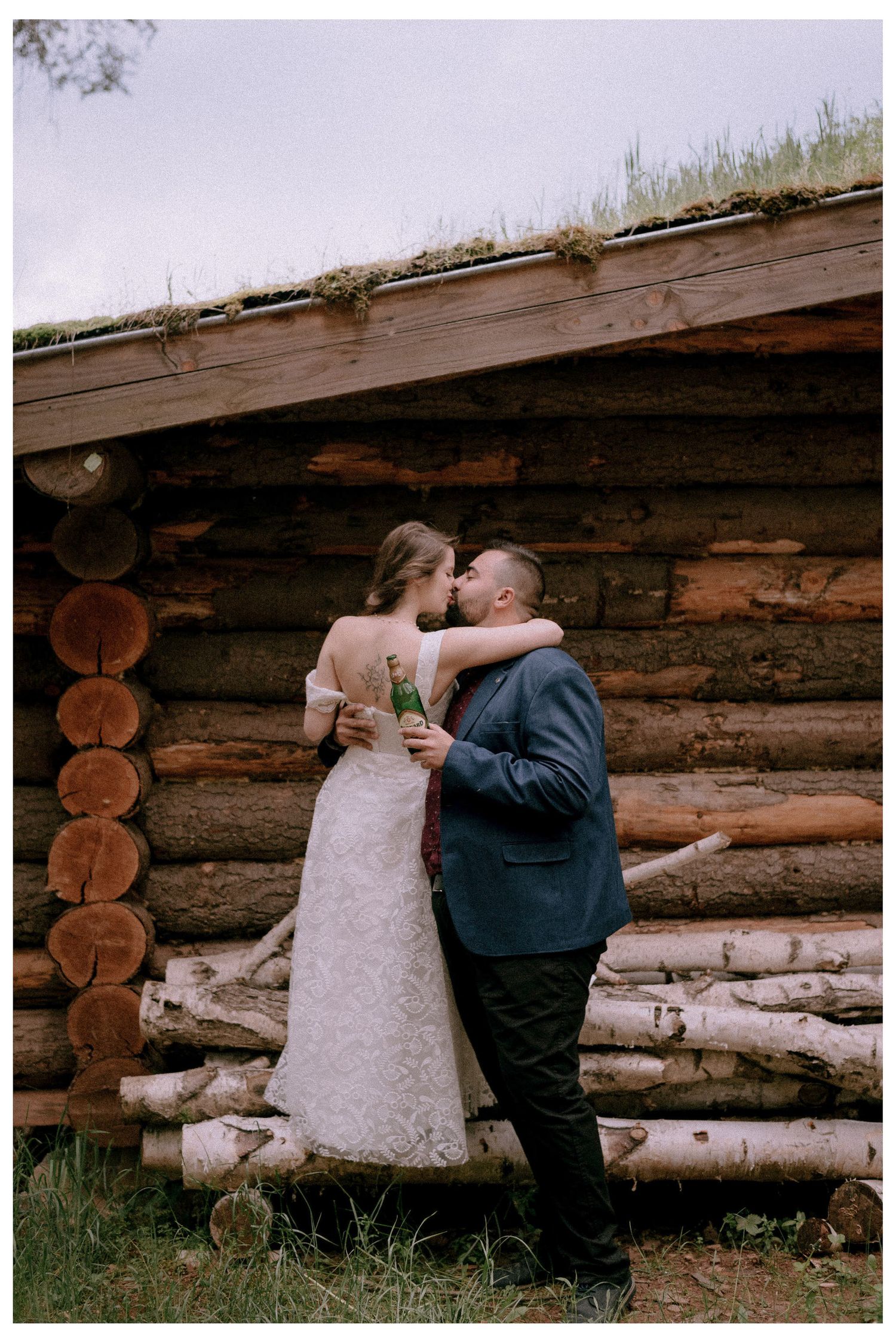 A couple shares an intimate moment against a rustic log cabin wall.