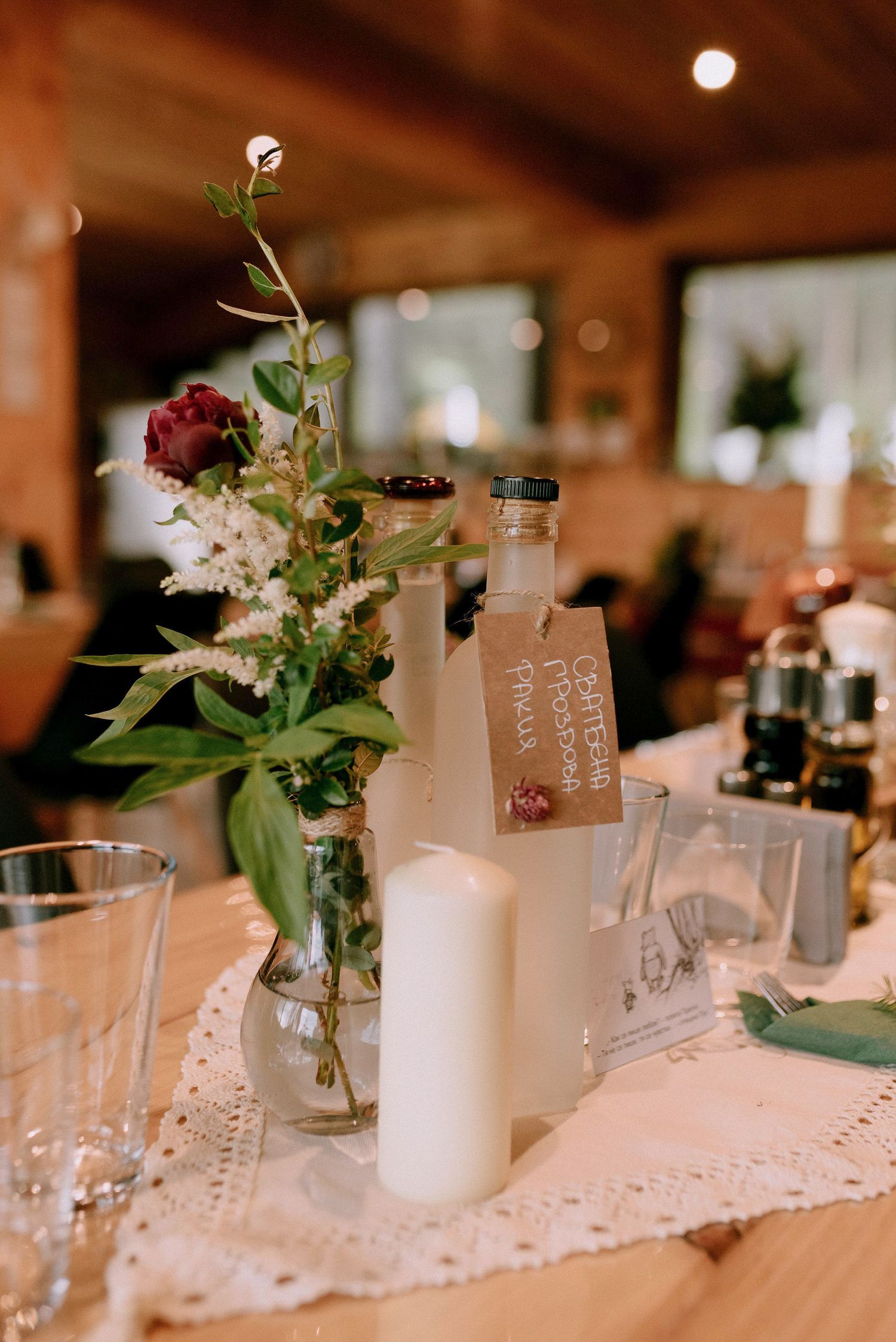Wedding reception table details with white lace runners, candles, and delicate floral arrangements.