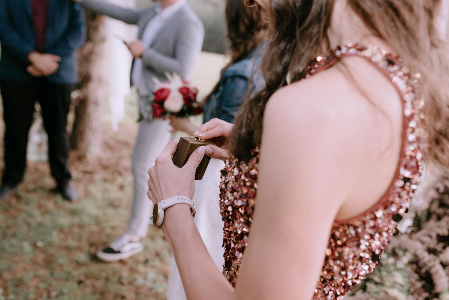 Wedding guests watching ceremony in rustic outdoor pine forest setting.