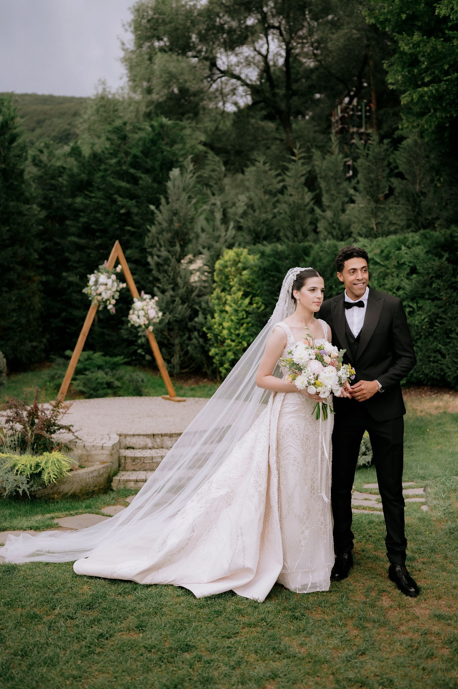 Elegant outdoor wedding ceremony setup with wooden arch and floral arrangements.