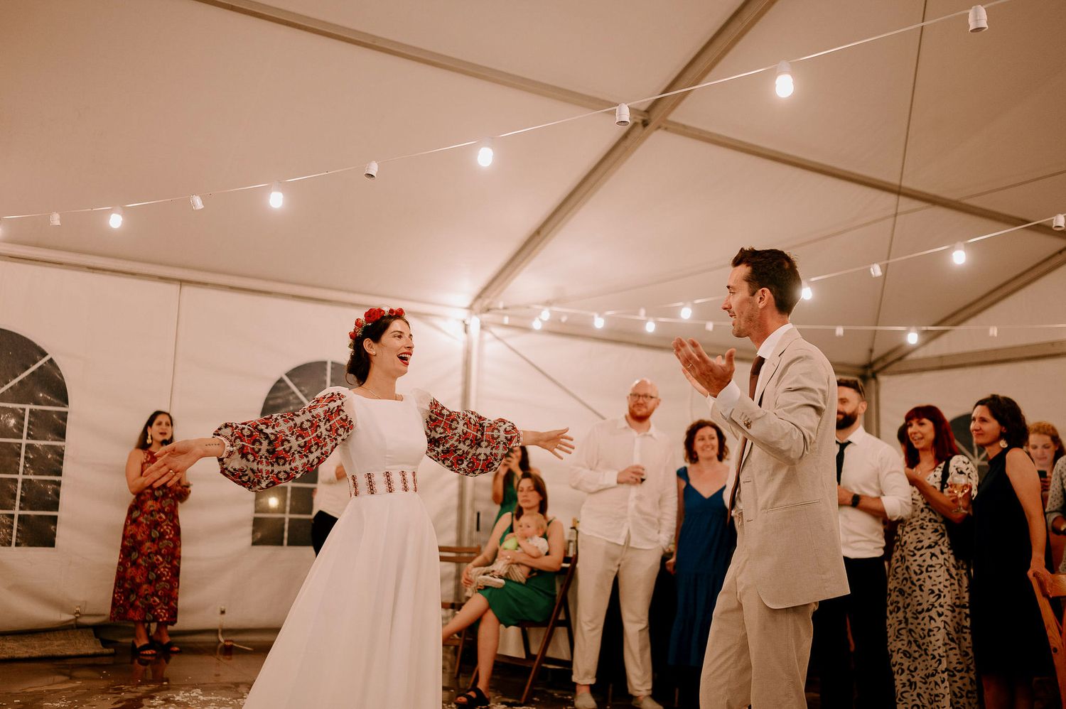 Evening wedding reception with guests dancing and celebrating in a decorated tent venue.