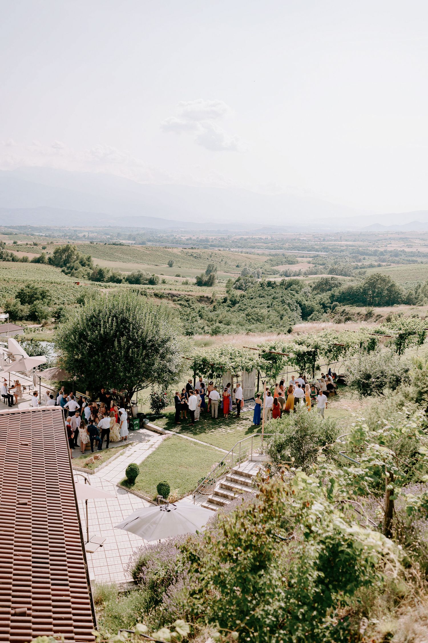 Wide angle view of a hilltop wedding ceremony location with guests gathered on stone steps.
