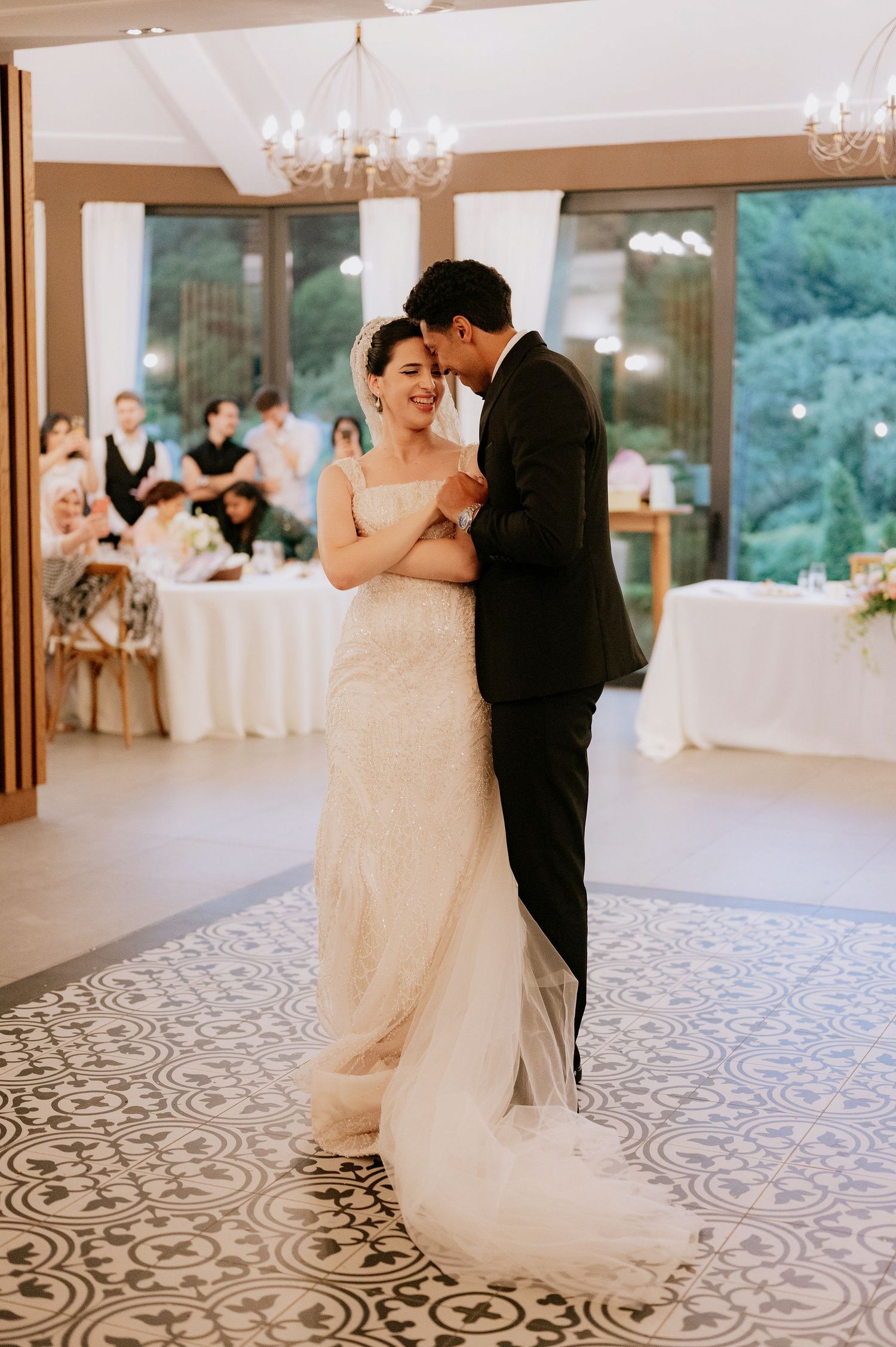 A romantic first dance moment in an elegant reception hall with chandeliers.