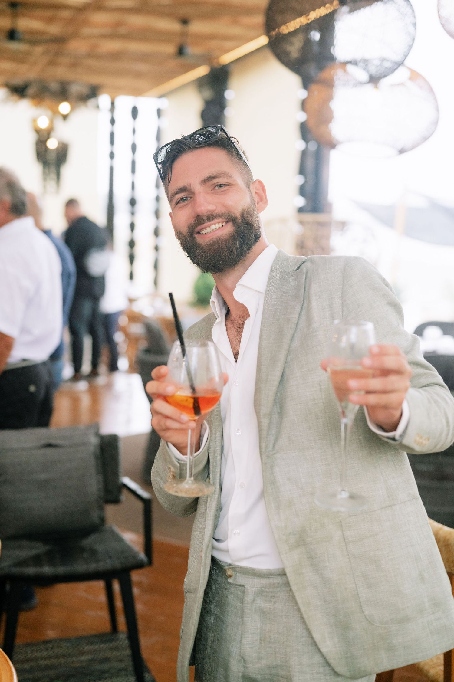 Guest in light gray suit holding cocktails at an elegant indoor venue.