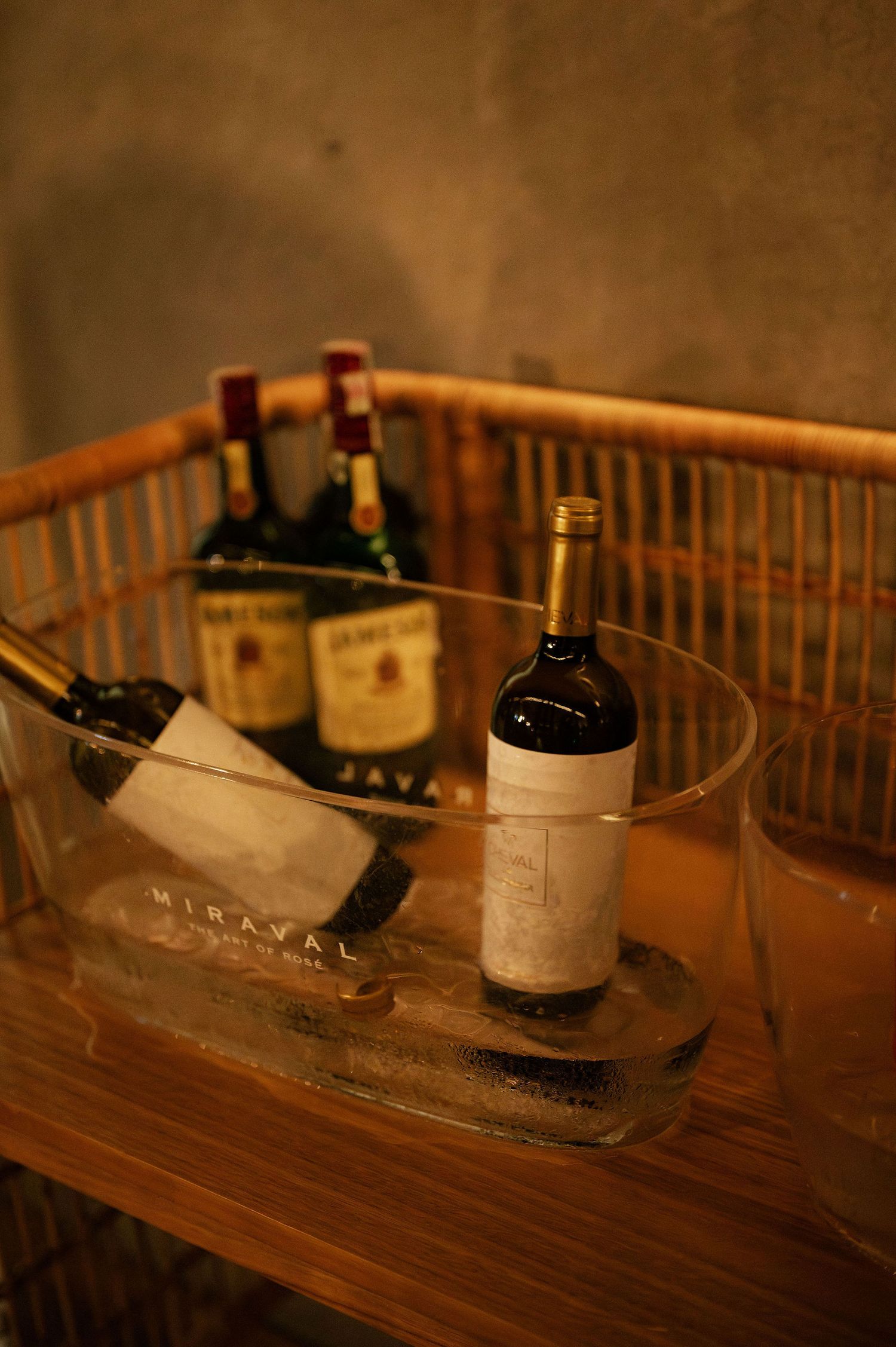 Wine bottles displayed in ice buckets on a wooden surface at an event.