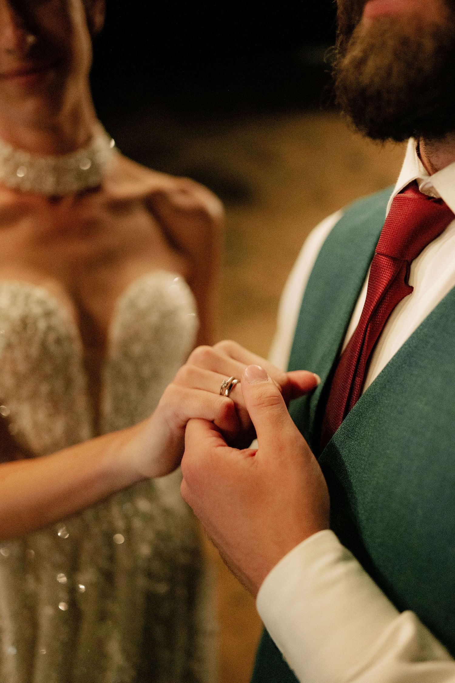 Close-up of formal wedding attire showing green vest and red tie details.